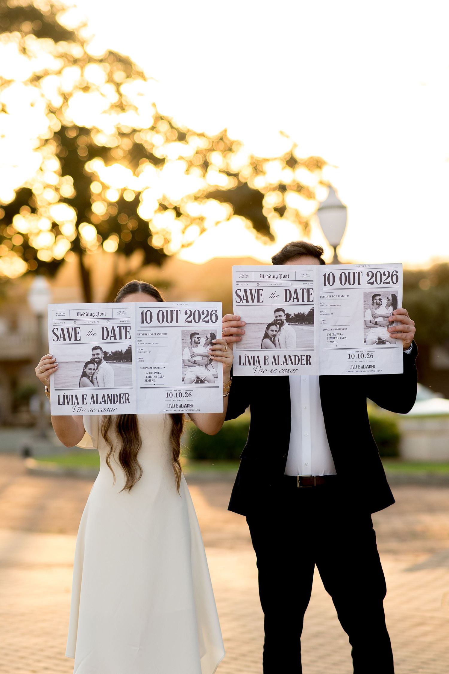 Couple holding Save the Date newspapers for Livia and Alander's October 2026 wedding during golden hour outdoors.