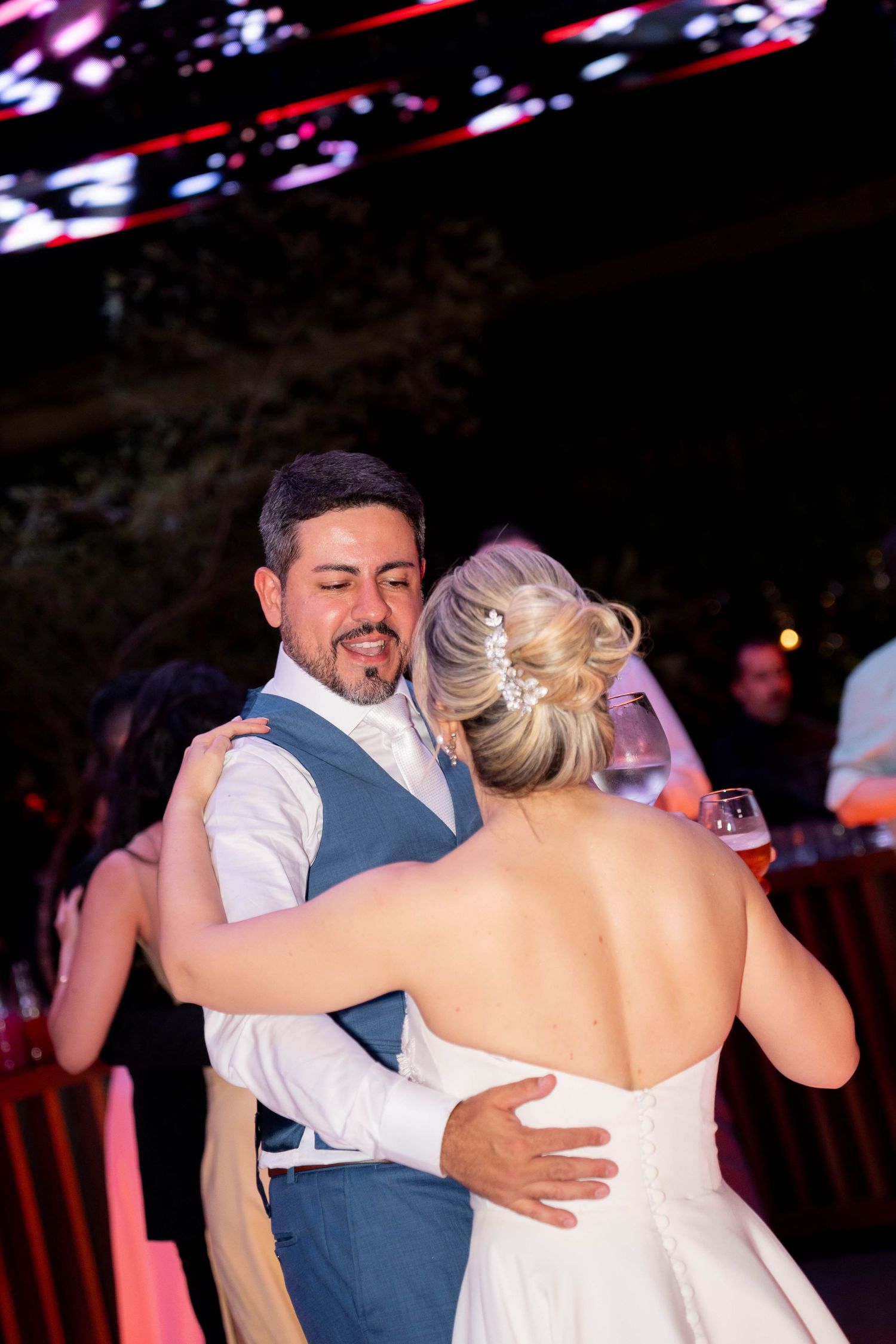 Bride and groom share their first dance, with the groom smiling warmly at his bride during their wedding reception.