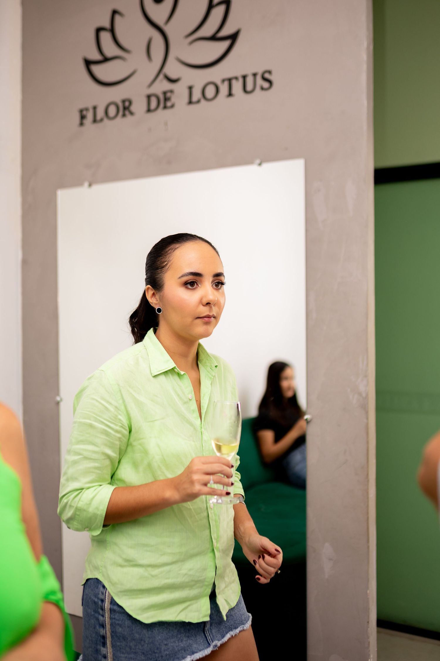 Woman in green linen shirt holding champagne glass at Flor de Lotus event.