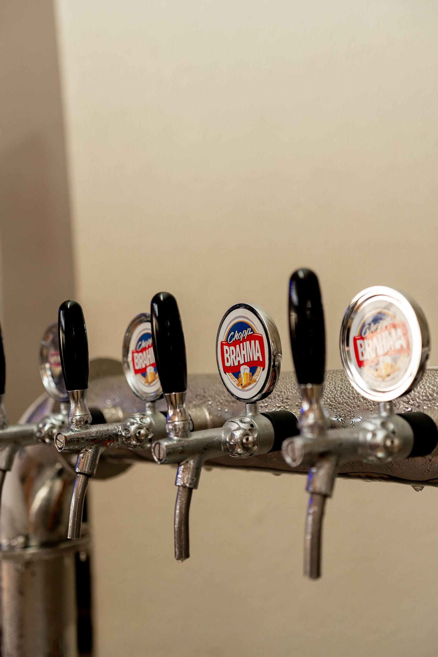 Close-up of chrome Brahma draft beer taps at a bar, featuring branded tap handles with black knobs.