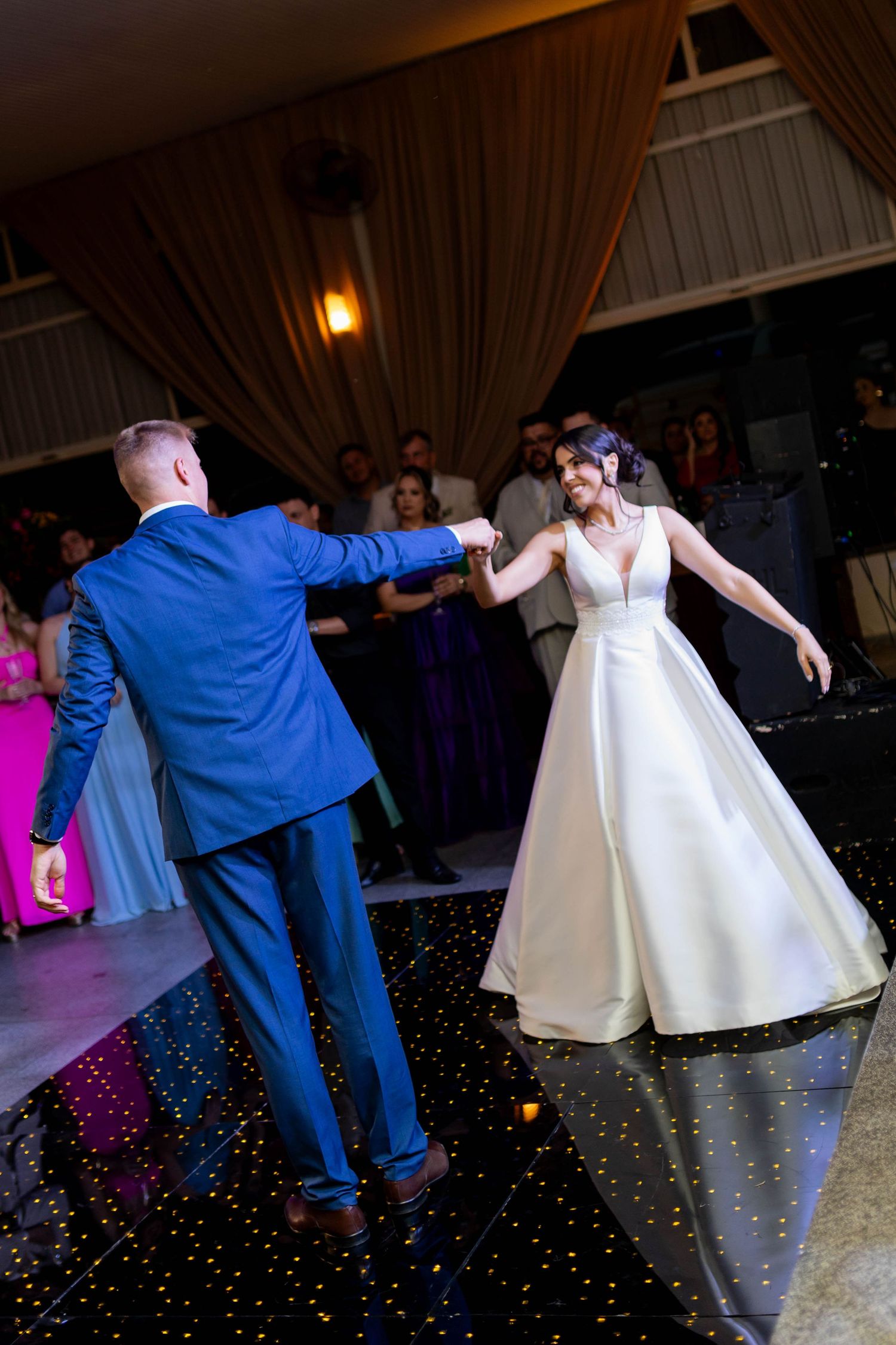 Bride and groom share their first dance on a starlit black dance floor at an elegant wedding reception.