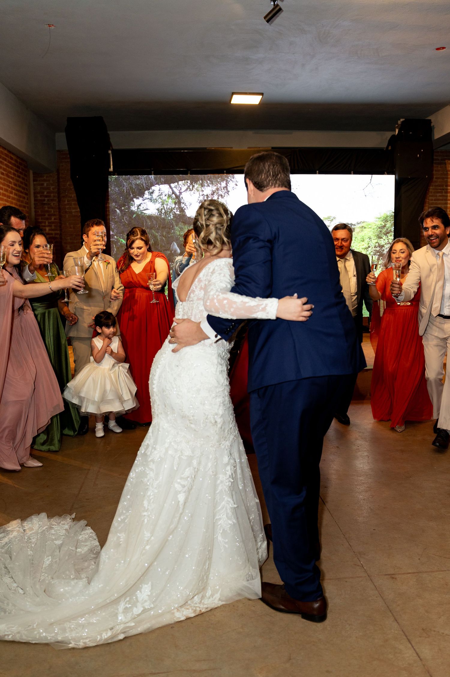 Bride and groom share their first dance surrounded by smiling guests at an elegant wedding reception venue.