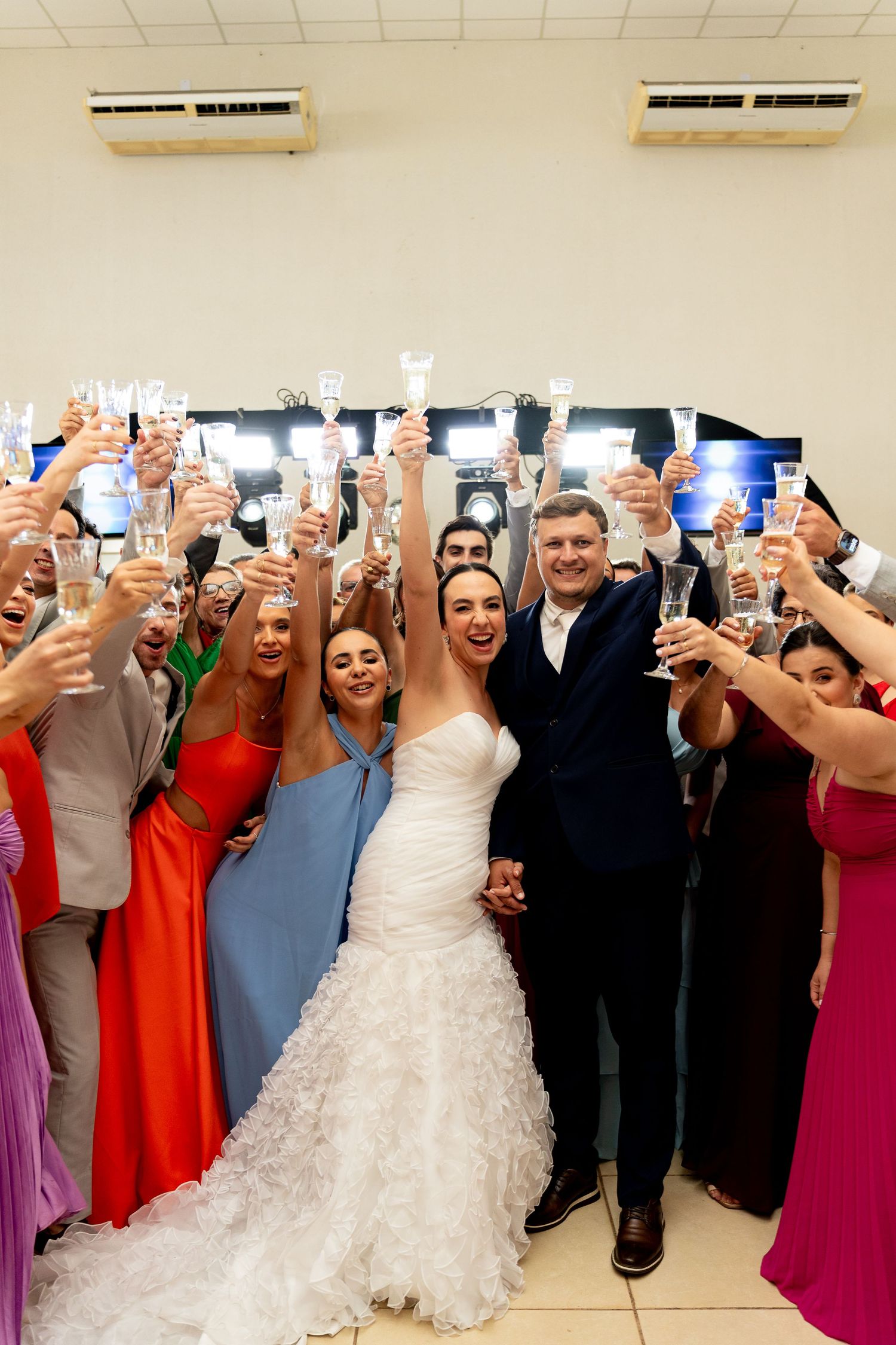 Bride and groom toast with guests raising champagne glasses at a joyful wedding reception celebration.