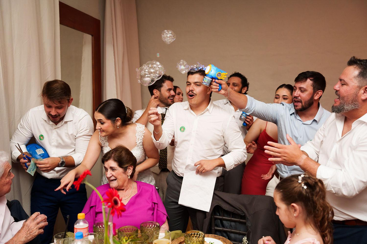 Joyful party celebration with guests dancing and laughing indoors, colorful decorations and festive atmosphere at a social gathering.