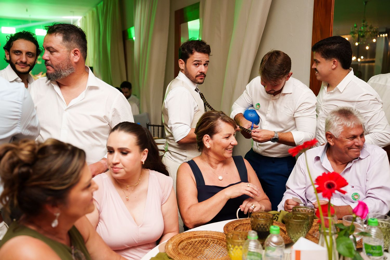 Guests socializing at an indoor wedding reception, seated at decorated tables in a warmly lit venue.