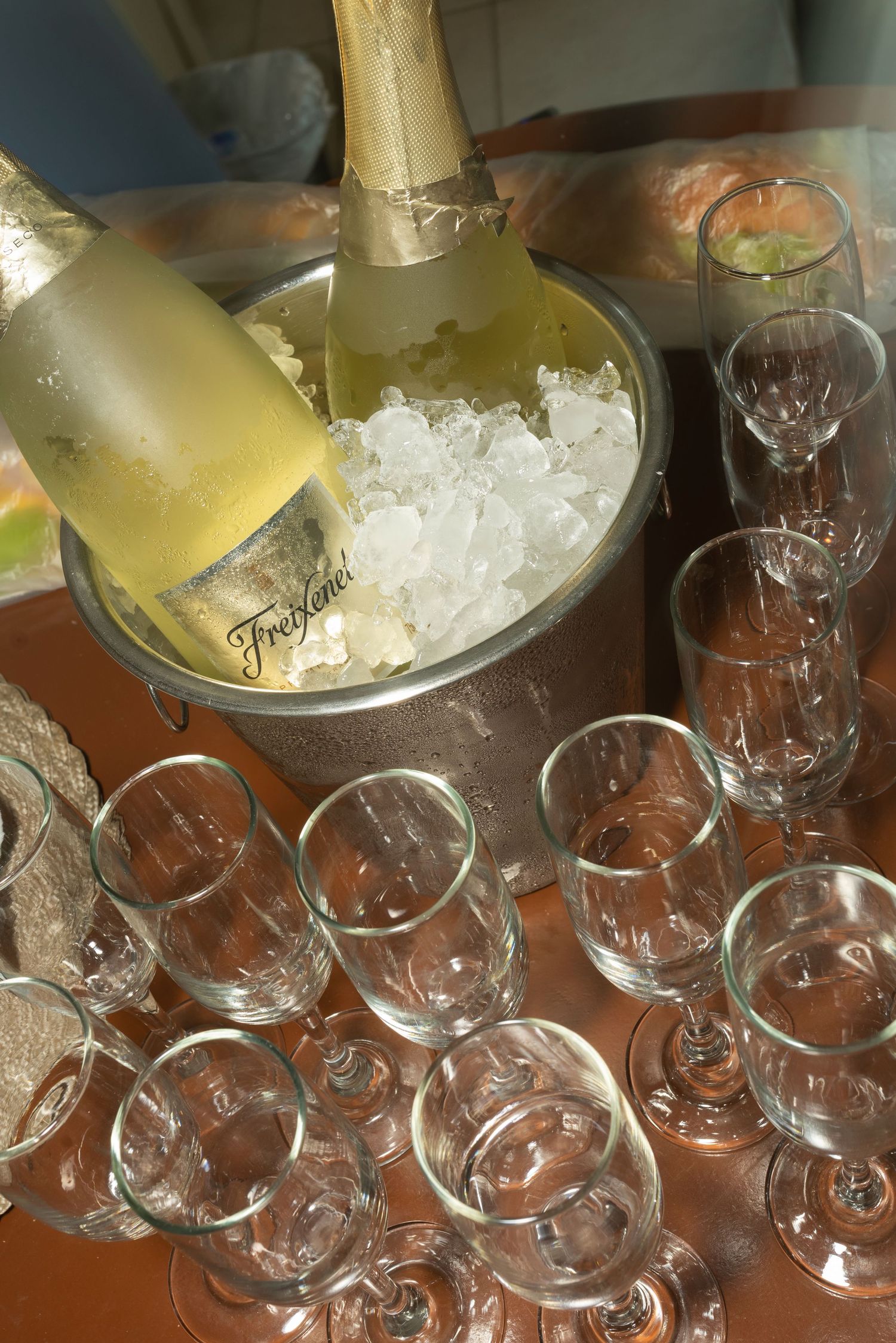 Freixenet champagne bottle chilling in ice bucket surrounded by empty wine glasses ready for celebration.