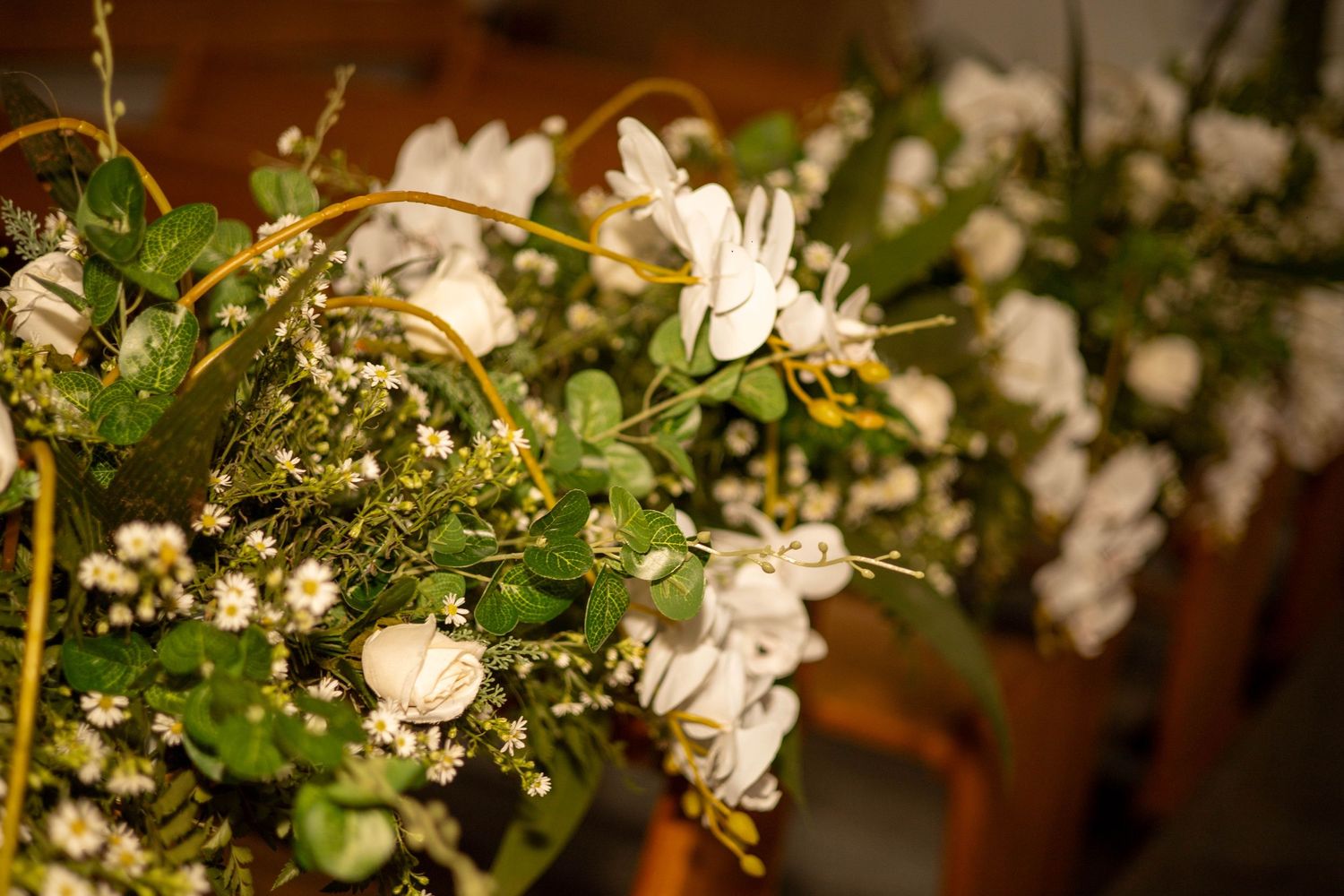 White floral bouquets with green foliage arranged on a table, featuring delicate white blooms and baby's breath.