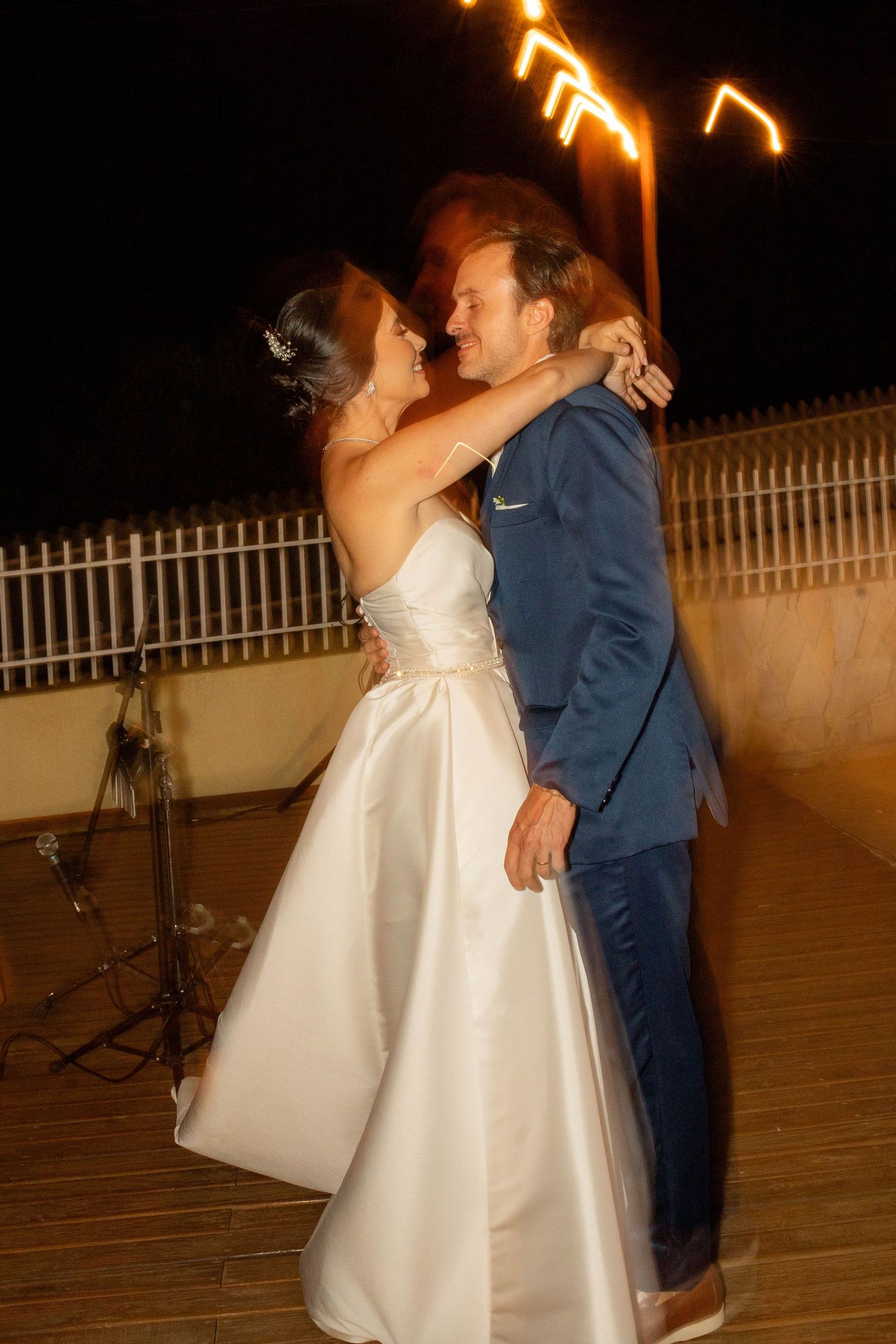 Bride and groom share a romantic first dance outdoors at night, with sparklers illuminating the celebration.