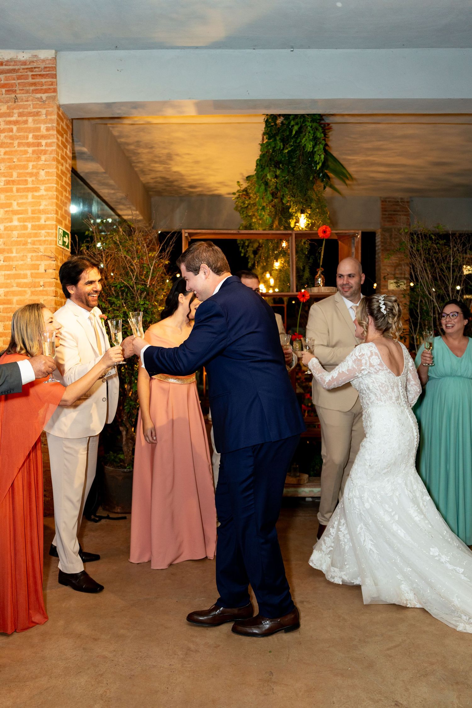 Bride and groom share first dance at wedding reception surrounded by guests in formal attire in decorated venue.