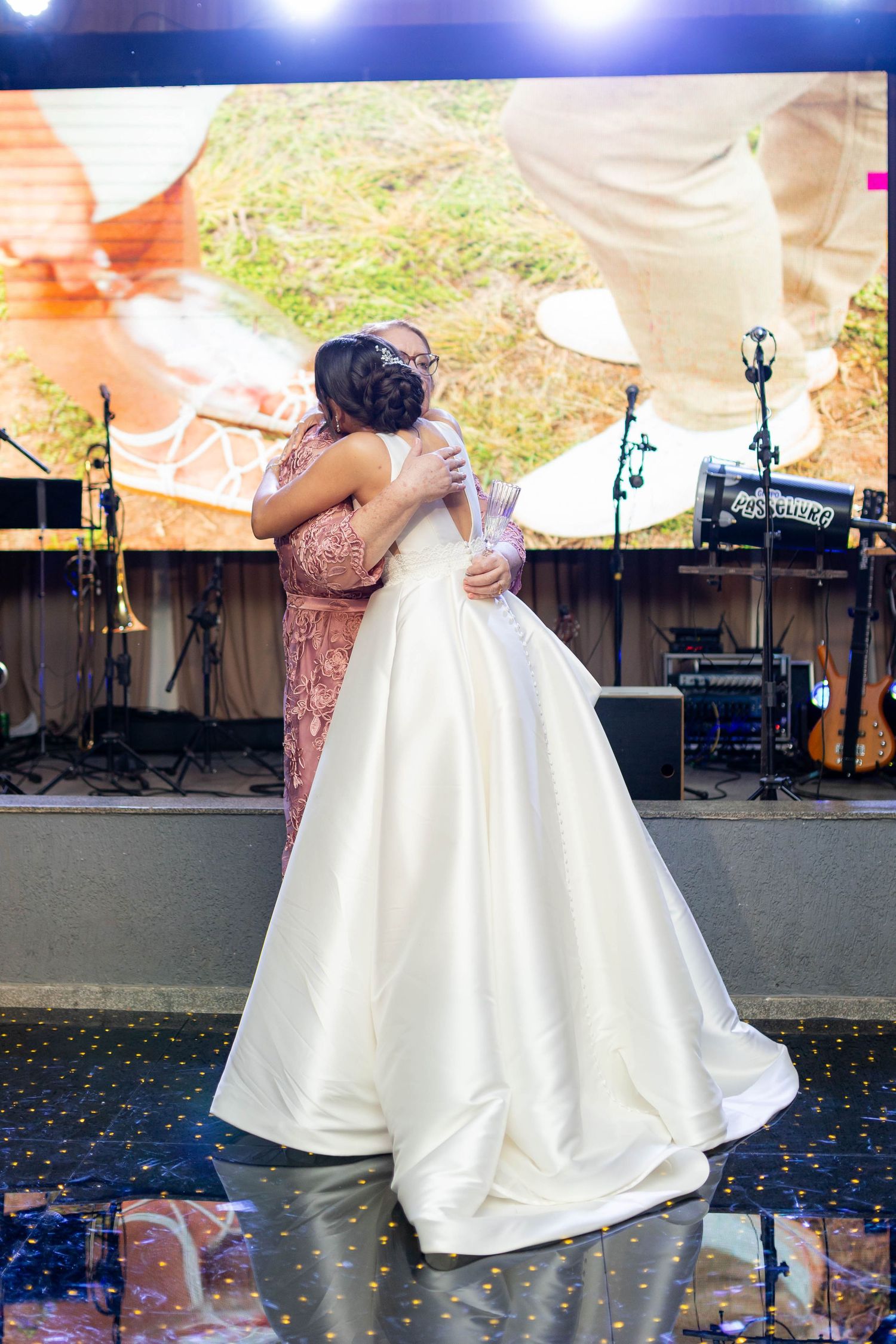 Bride in white ball gown sharing a heartfelt hug on the dance floor at an elegant wedding reception.