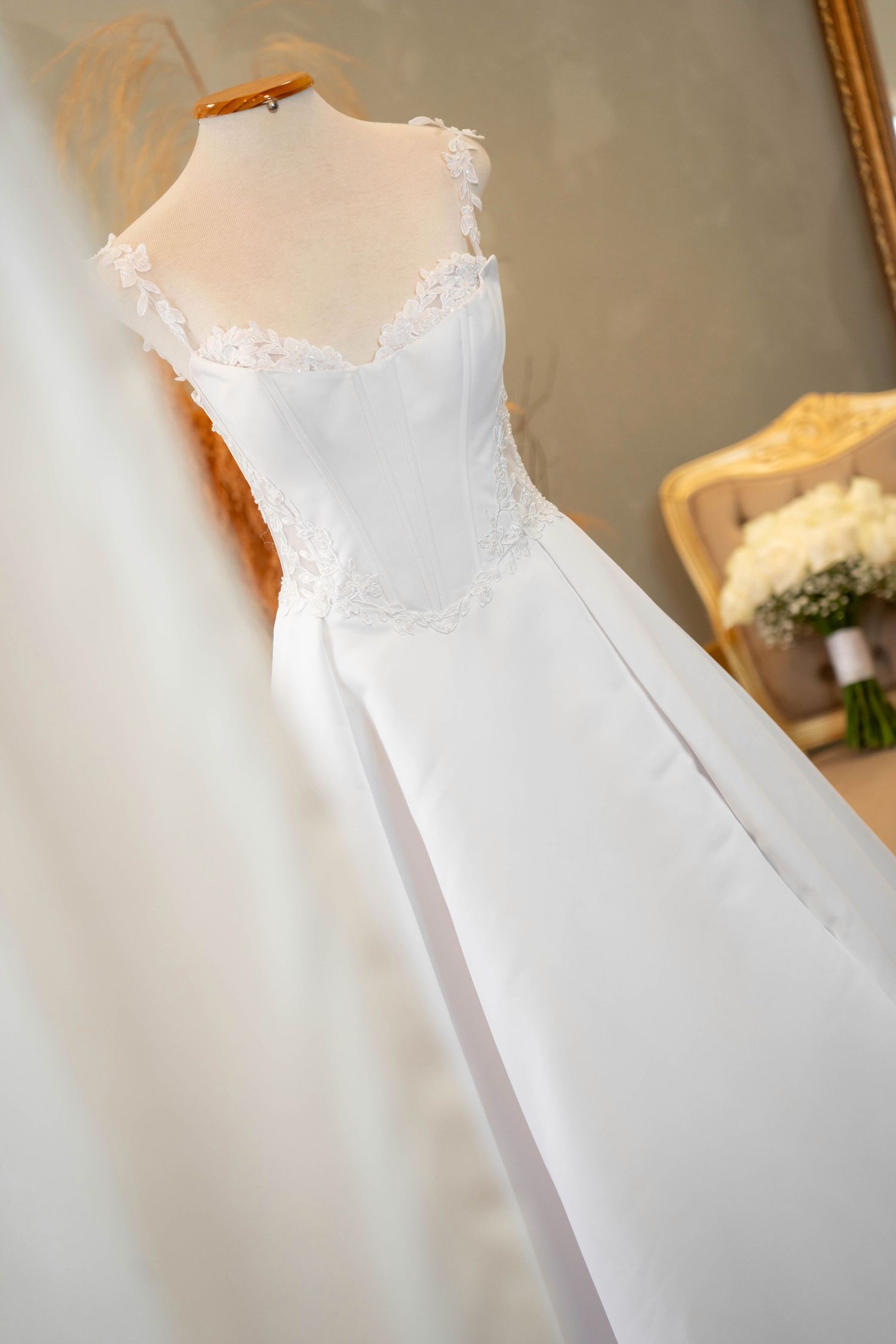Elegant white wedding dress on a mannequin, featuring lace bodice and flowing skirt in a bridal boutique.