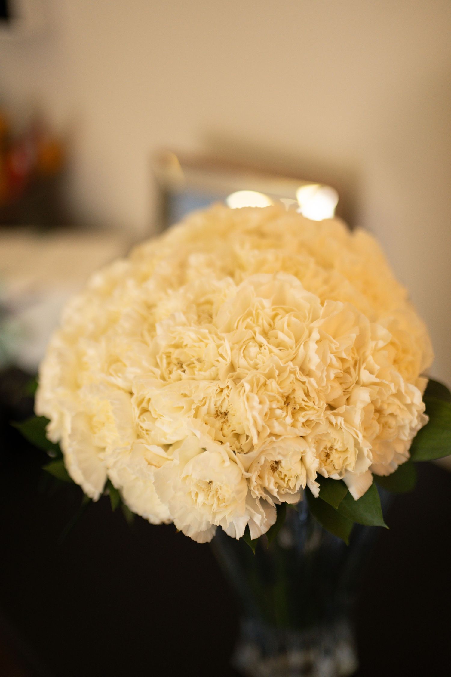Elegant bouquet of white carnations arranged in a glass vase, perfect for weddings or home decor.
