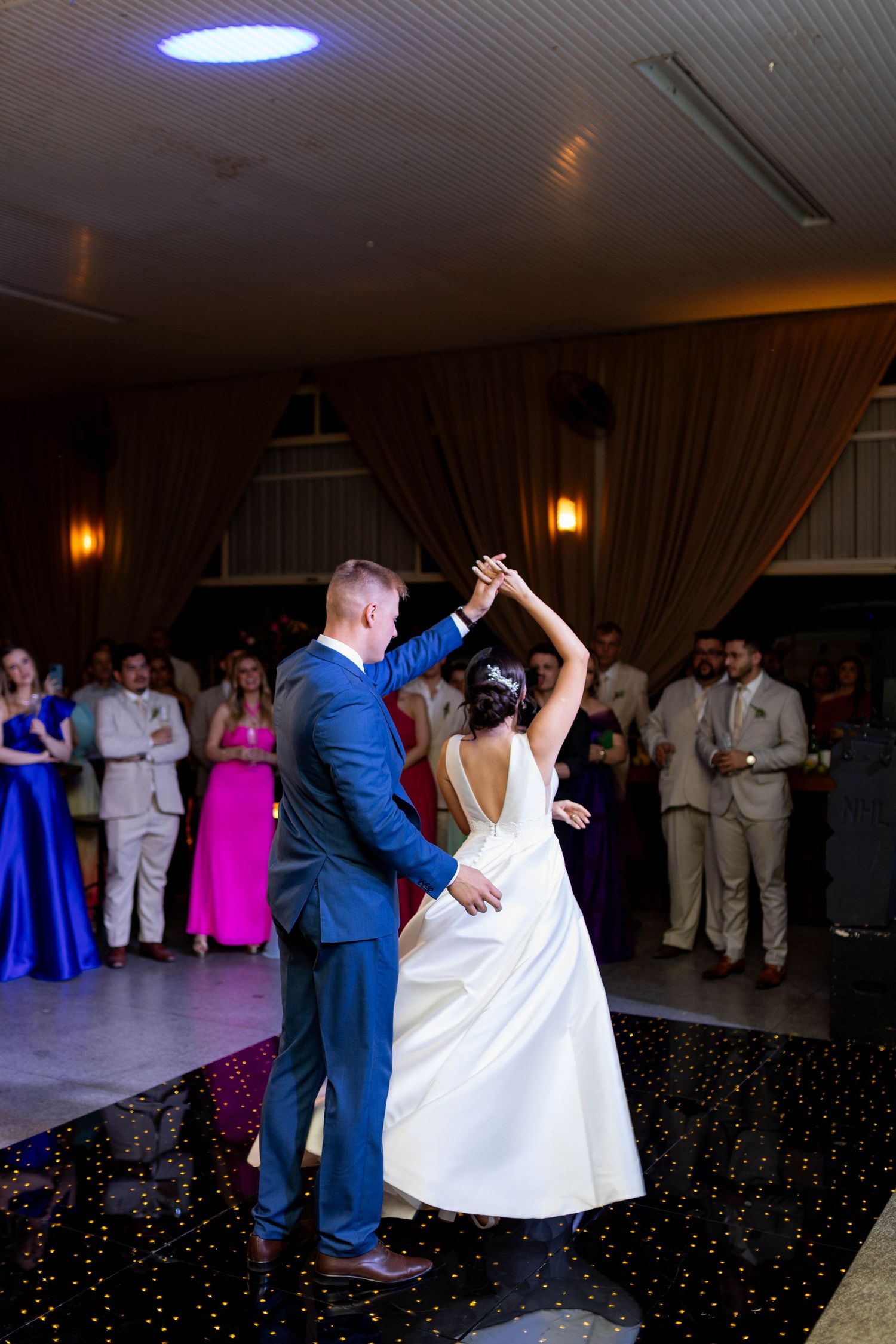 Bride and groom share their first dance at wedding reception while guests watch in elegant venue.