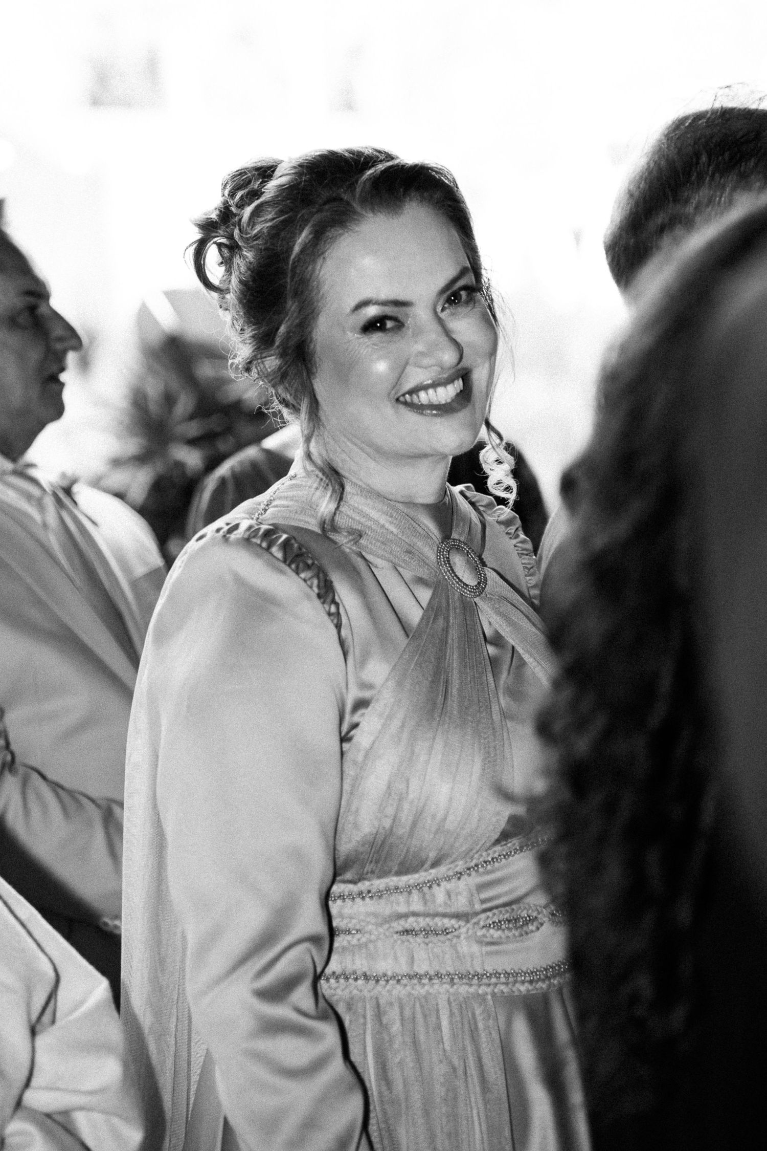 Smiling woman in elegant dress at a social gathering, black and white photo.