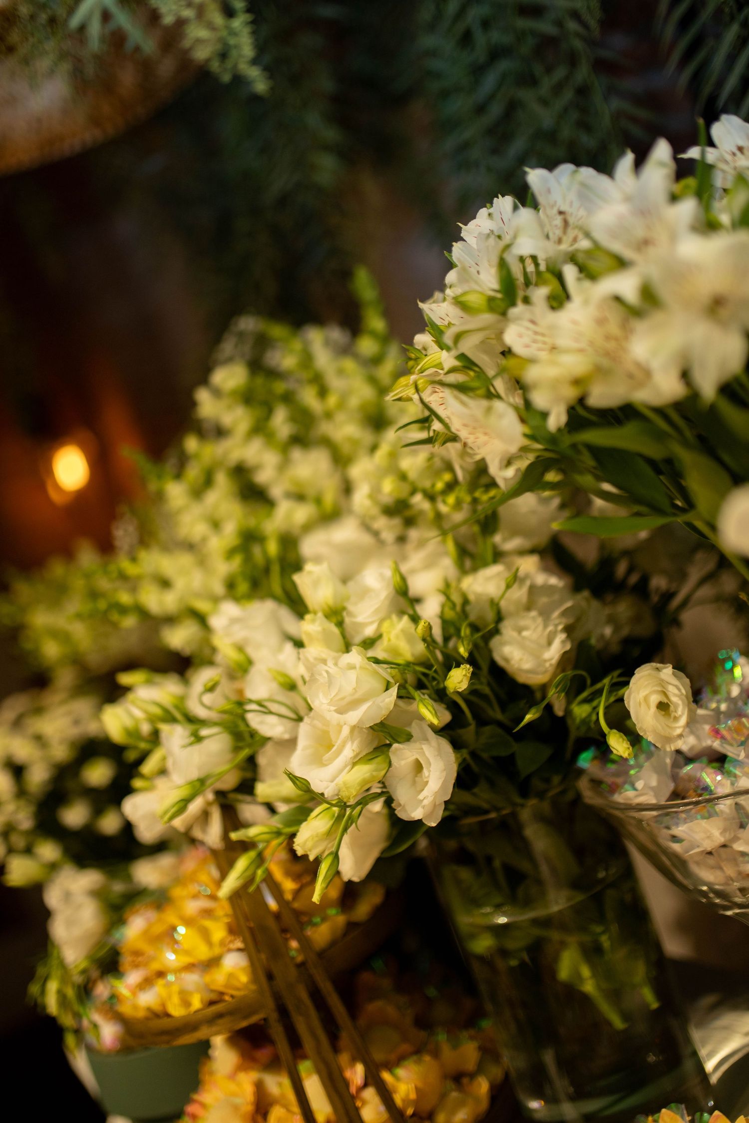 Elegant white freesia and ranunculus flower arrangements in glass vases displayed at a formal event or wedding reception.