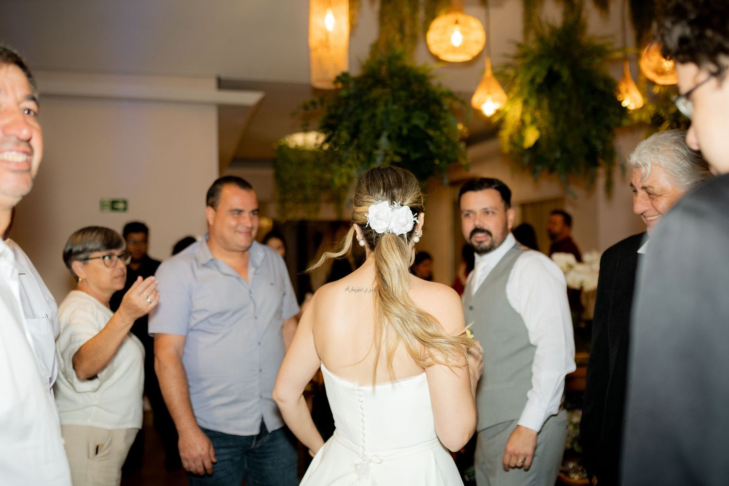 Bride in white dress dancing with guests at elegant indoor wedding reception with warm lighting.