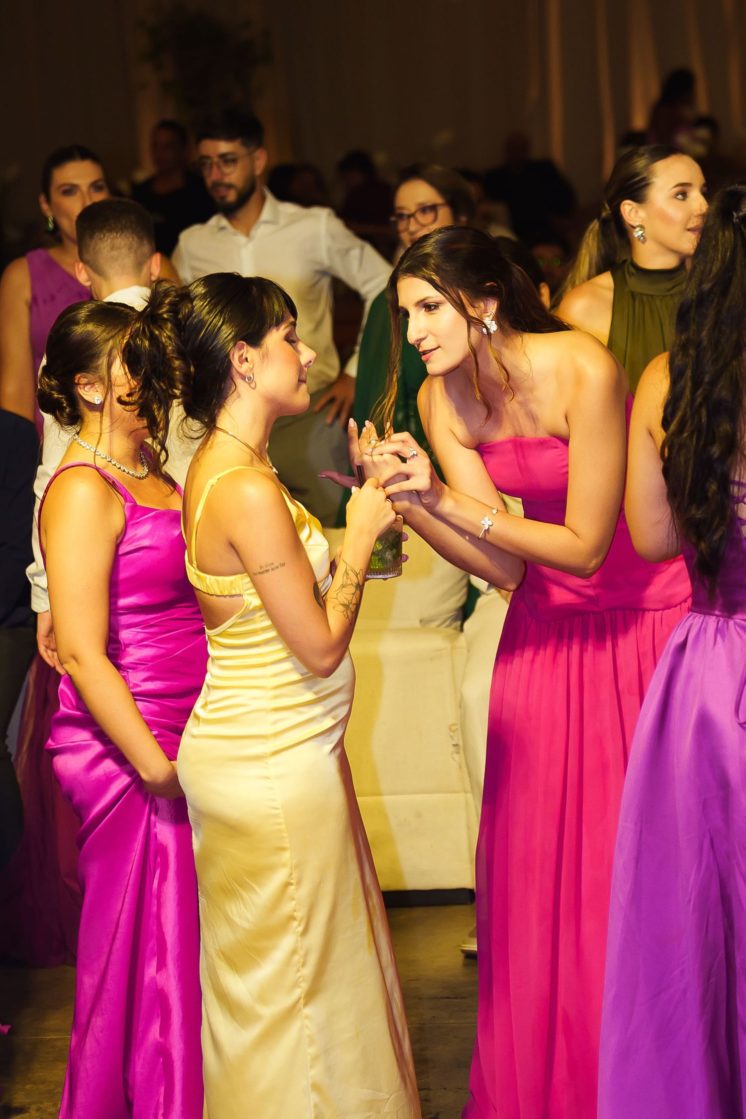 Young women in colorful formal gowns socializing at an elegant prom or gala event.