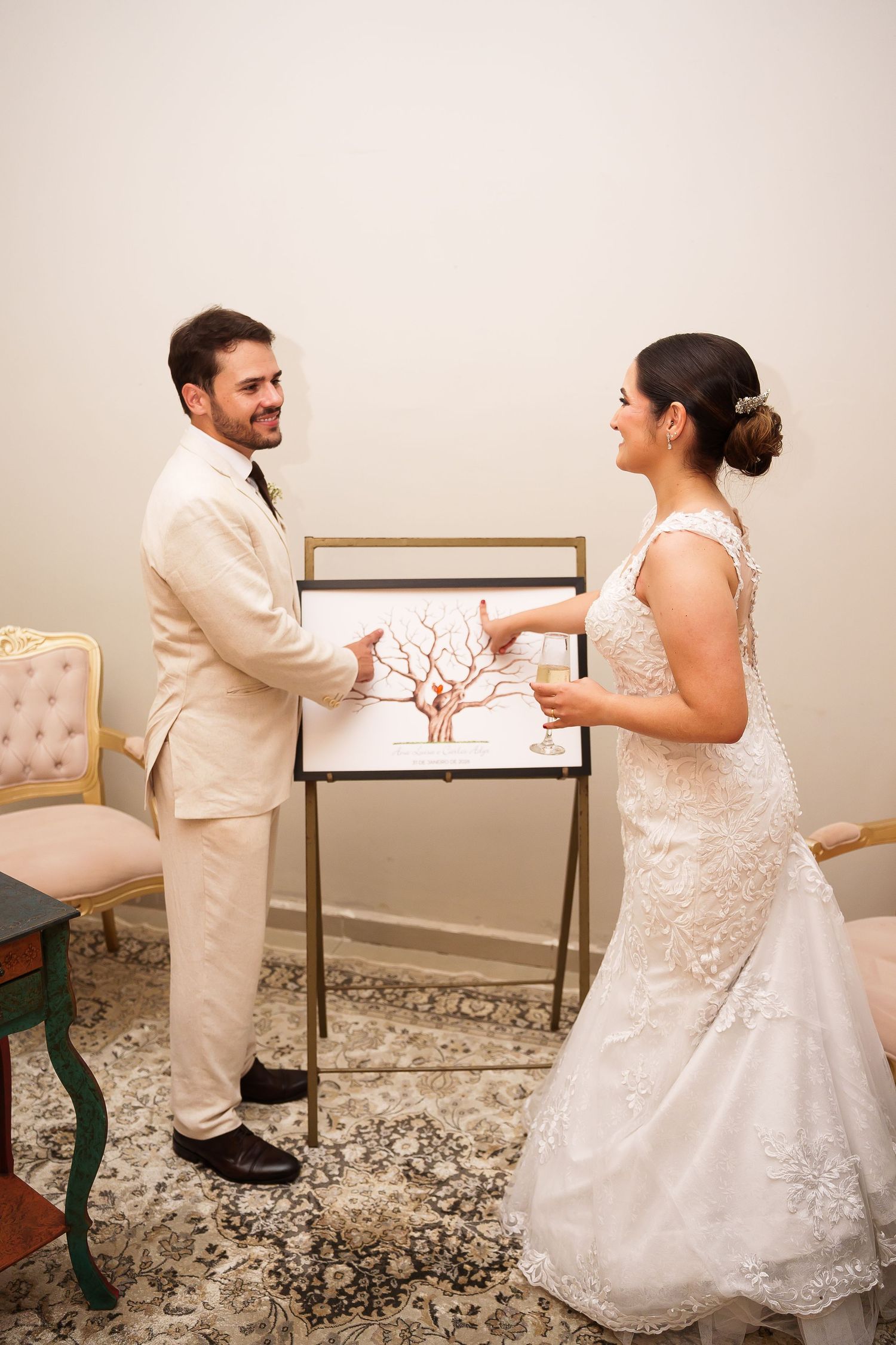 Bride and groom smiling while holding a fingerprint tree guest book artwork at their elegant wedding reception.