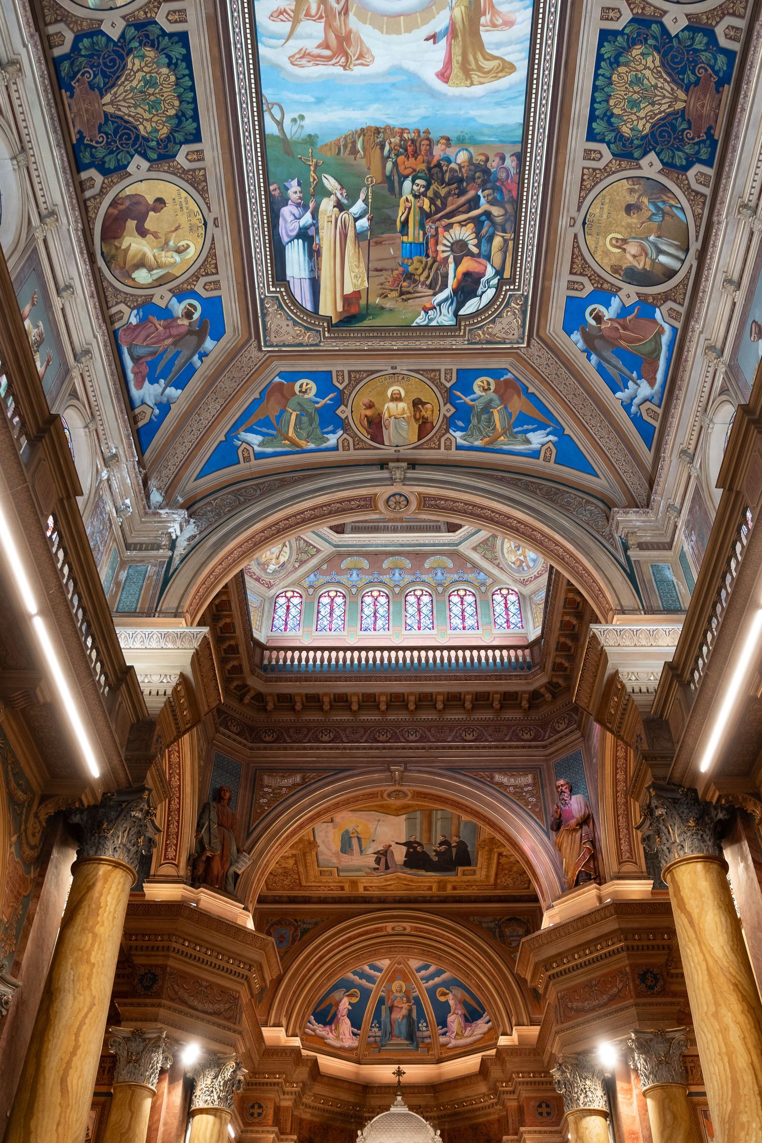 Ornate cathedral ceiling with vibrant religious frescoes, gold arches, and colorful biblical scenes painted in classical style.