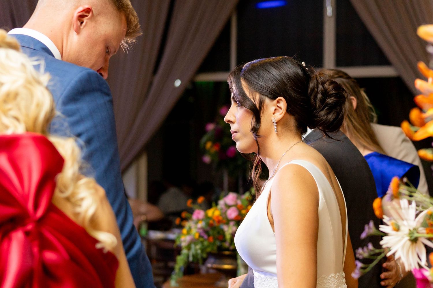 Bride and groom sharing a moment at wedding reception with colorful floral arrangements in background.