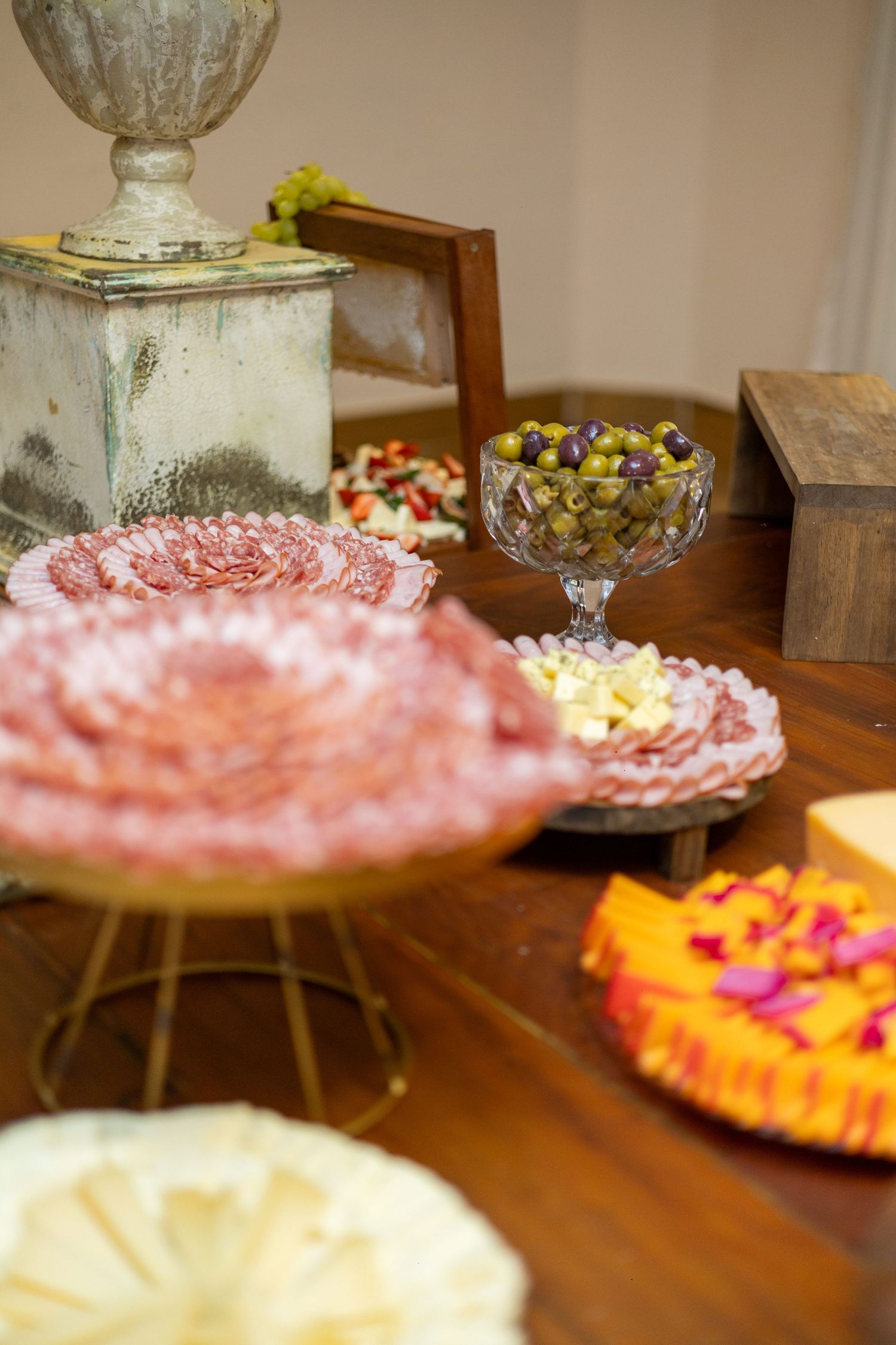 Elegant charcuterie spread with salami roses, olives, cheese, and colorful garnishes on a rustic wooden table.