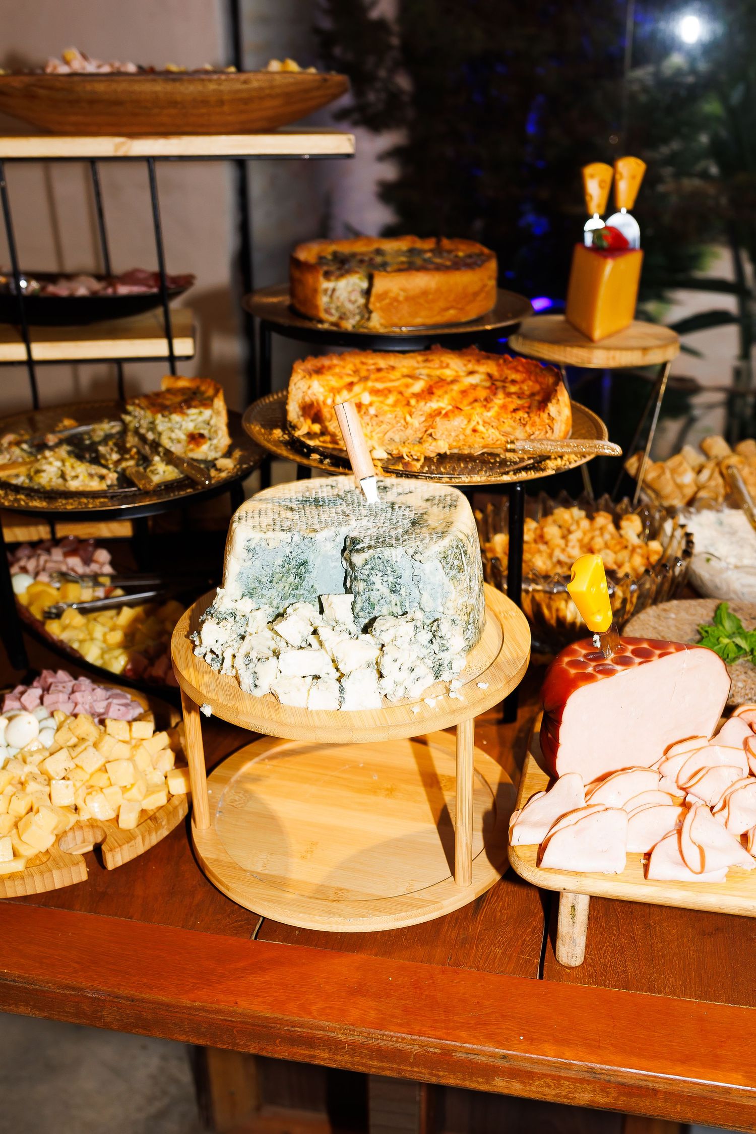 Elegant charcuterie spread featuring blue cheese, cured meats, assorted pastries, and gourmet appetizers on a wooden table.