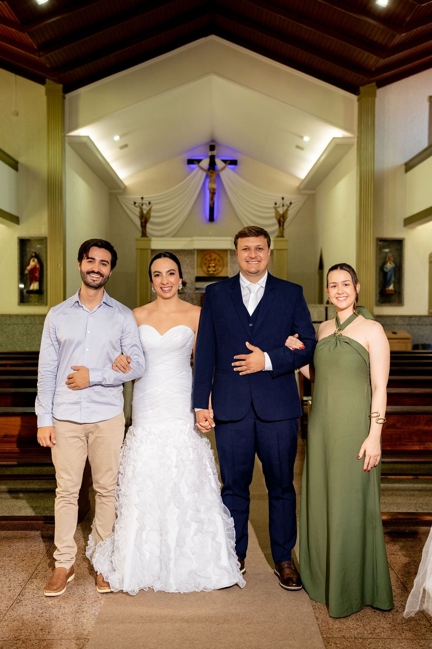 Bride and groom pose with two guests inside a church after wedding ceremony.