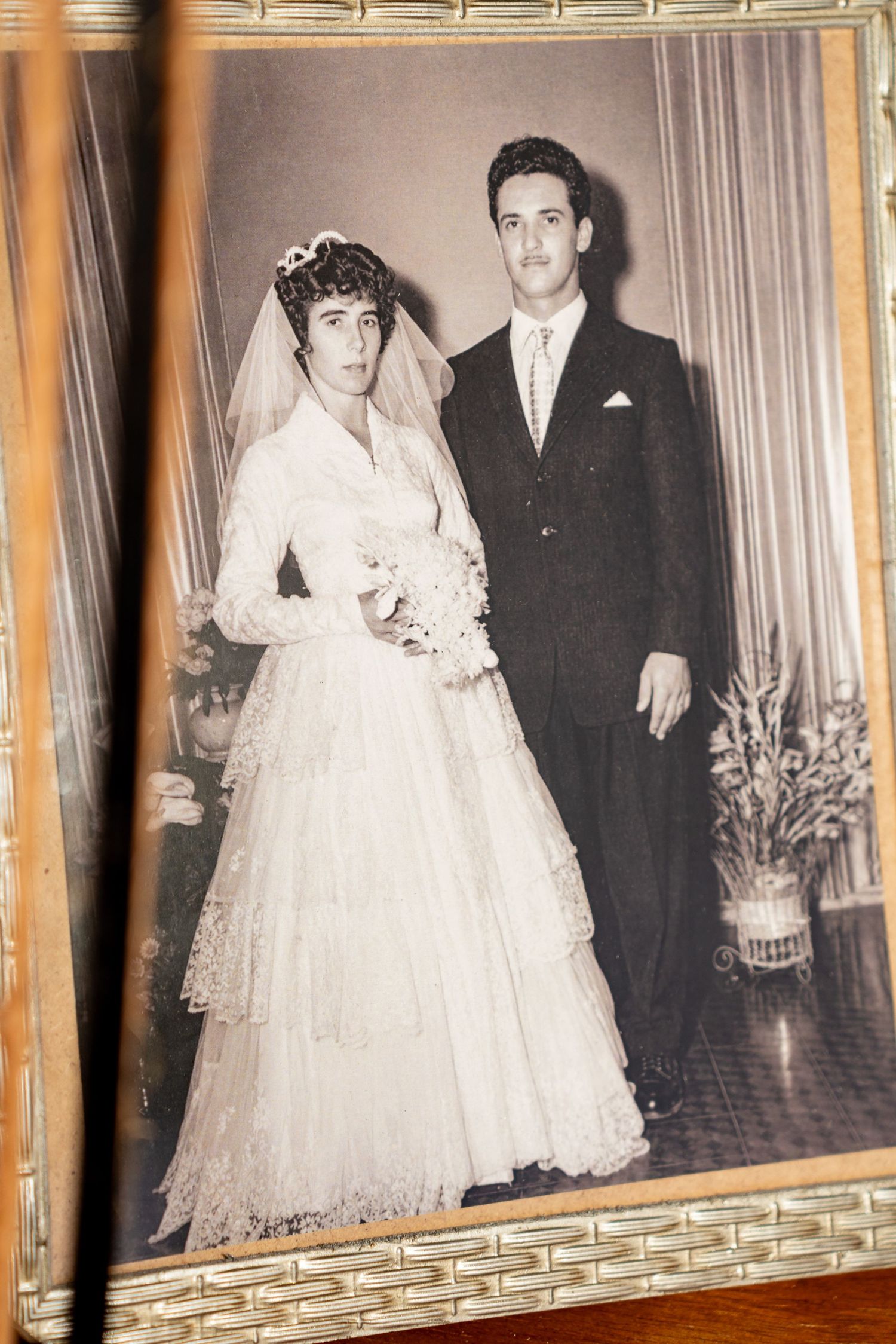 Vintage black and white wedding photo of a bride in lace gown with veil and groom in dark suit.