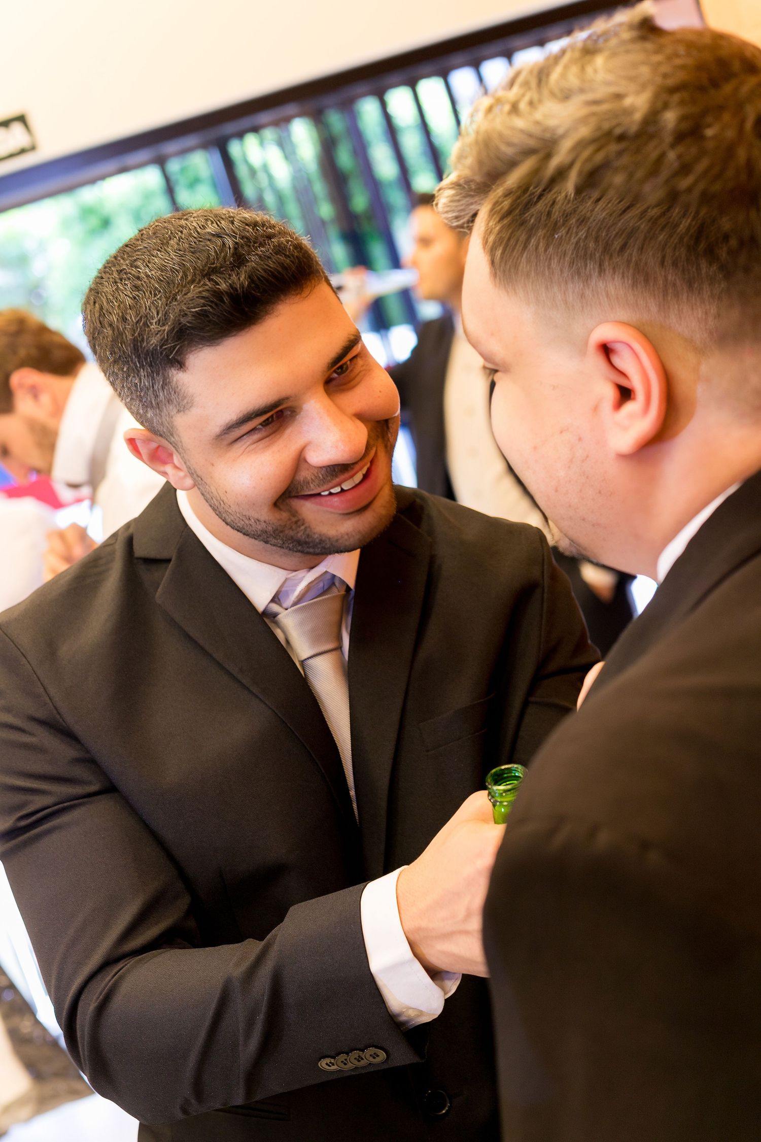 Two men in dark suits smiling and shaking hands at a formal event.