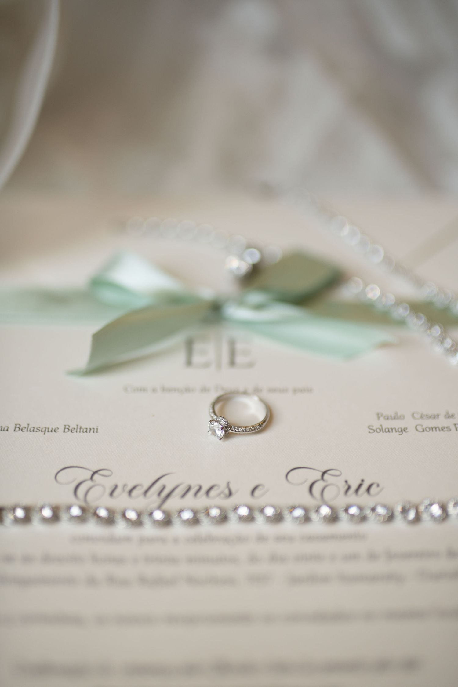 Elegant wedding invitation for Evelynes and Eric with diamond ring, pearl necklace, and mint green ribbon bow.