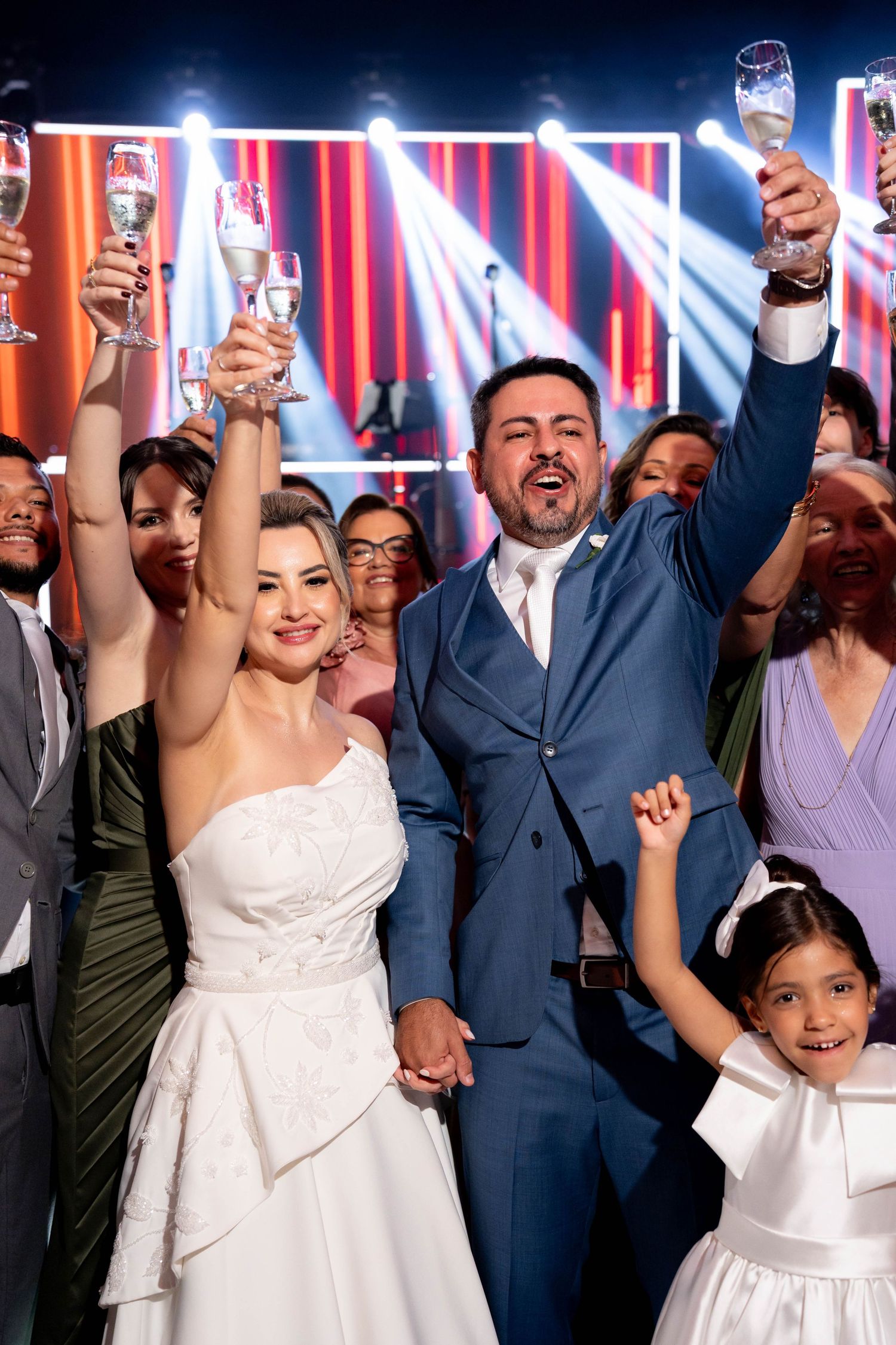 Joyful bride and groom raising champagne glasses with wedding guests during a festive reception celebration.