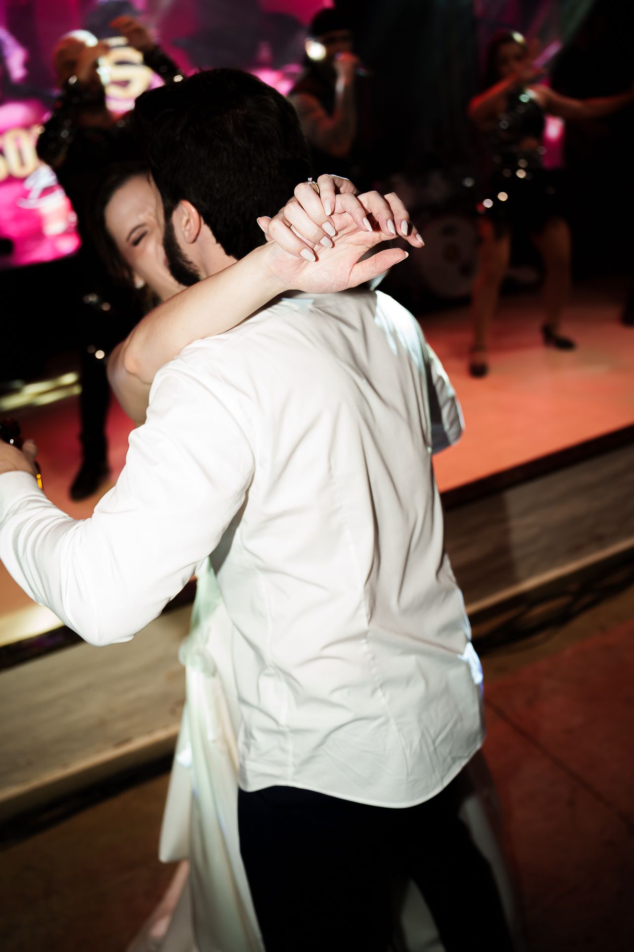 Couple sharing a romantic first dance at a wedding reception with a live band performing on stage in the background.