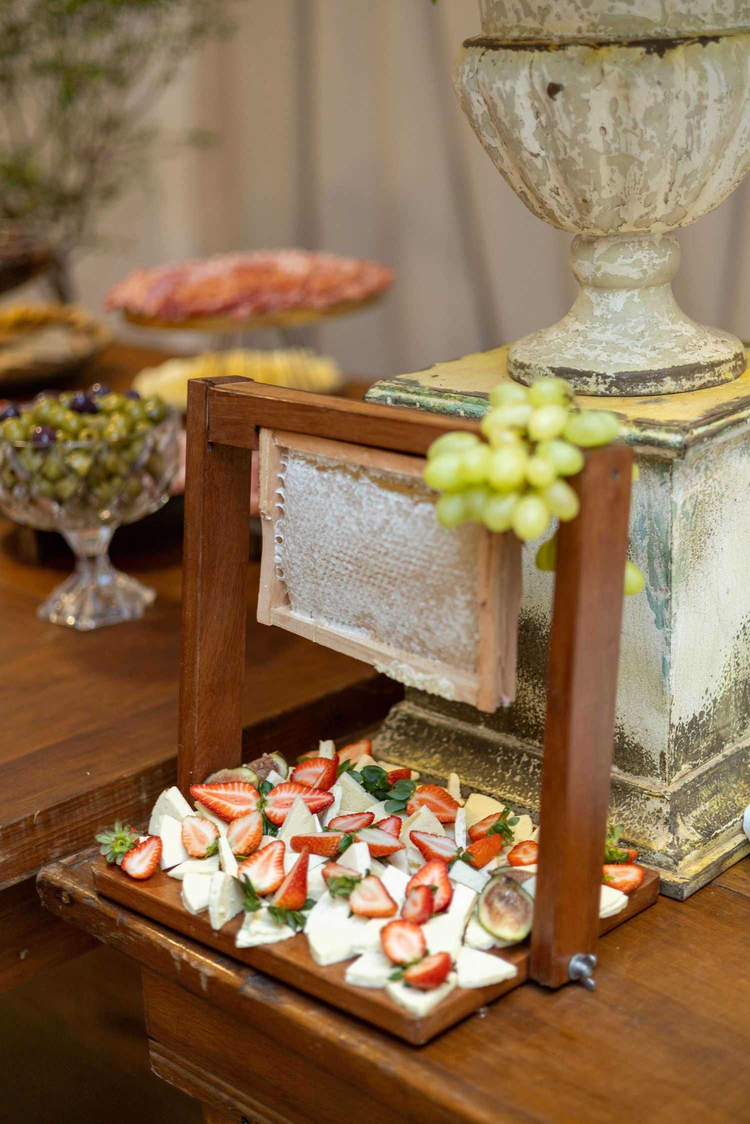 Elegant catering display with fresh strawberries, mozzarella, and grapes on a wooden tiered stand at a formal event.