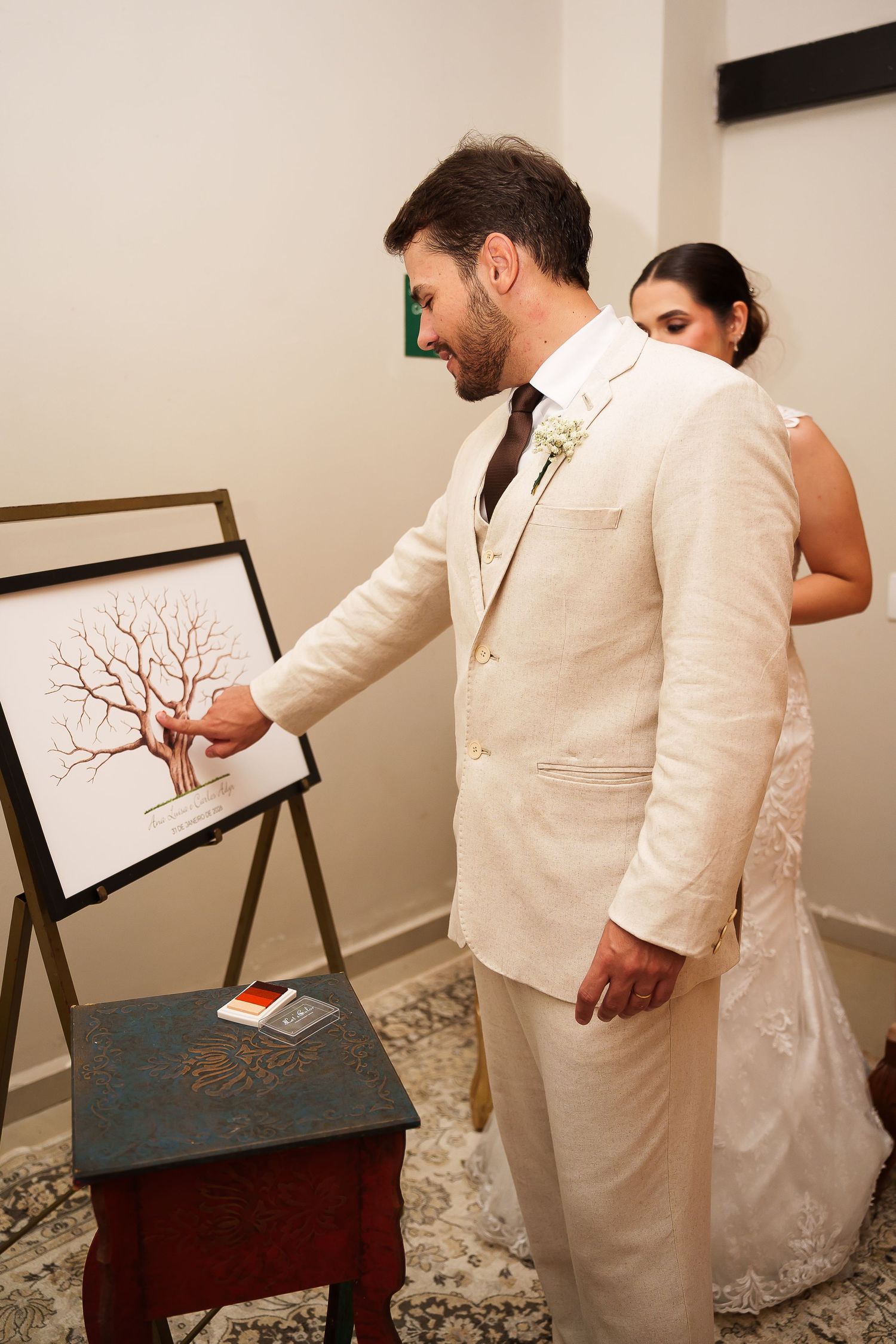 Bride and groom signing a fingerprint tree guest book at their wedding reception on an easel.