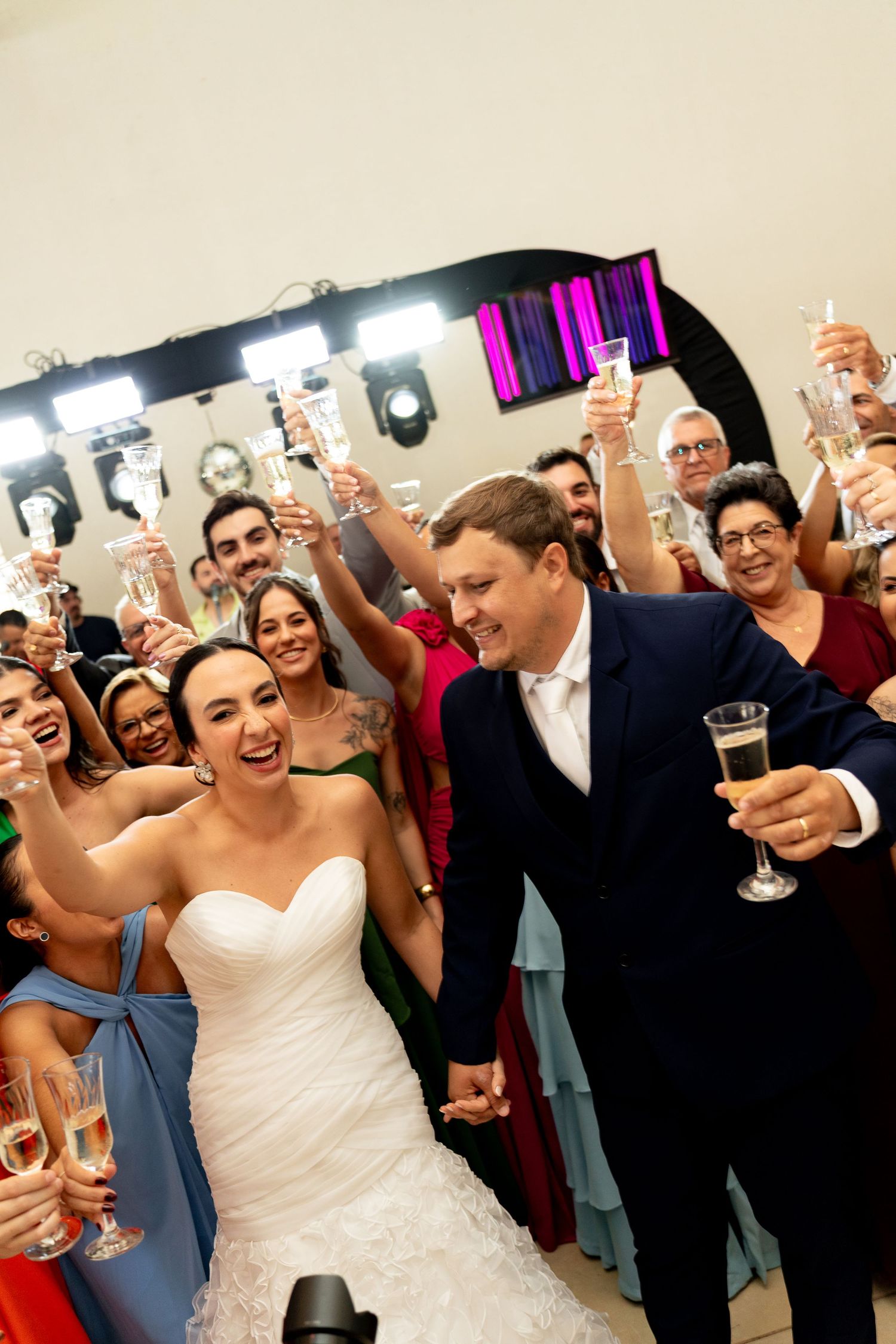 Bride and groom toast champagne with smiling wedding guests at a festive indoor reception celebration.