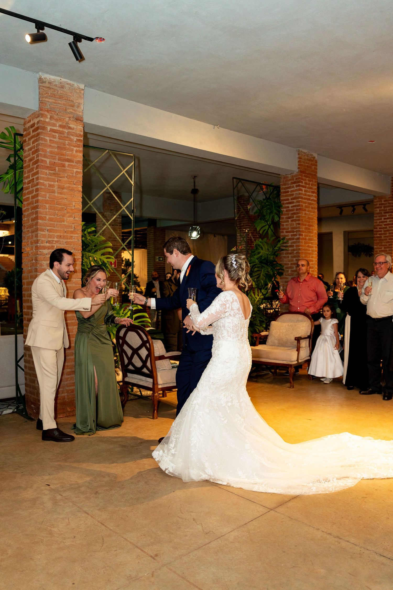Bride and groom share first dance at elegant wedding reception with guests watching and brick pillars in background.