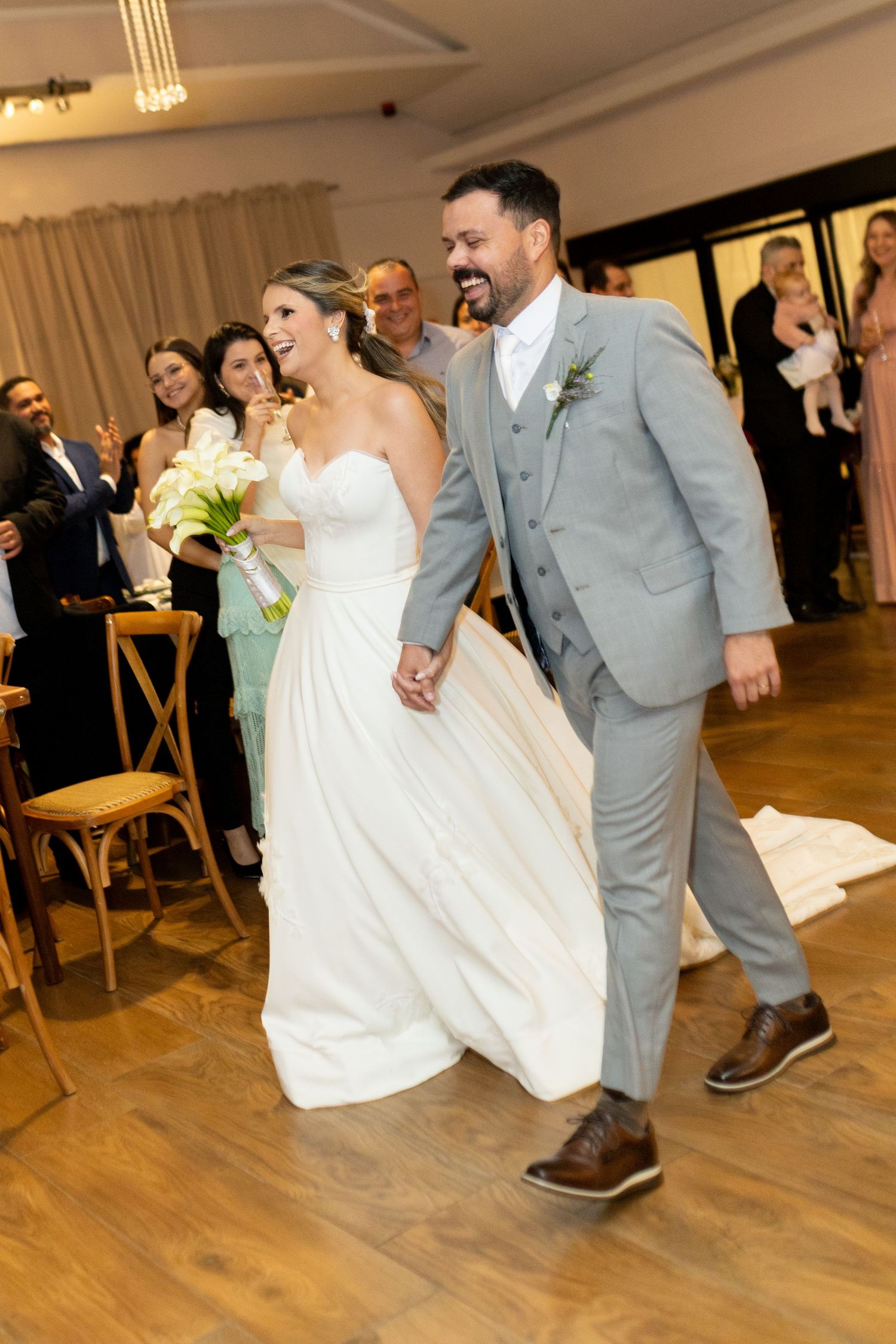 Bride and groom walk hand in hand down the aisle, smiling joyfully, as guests celebrate their wedding ceremony.
