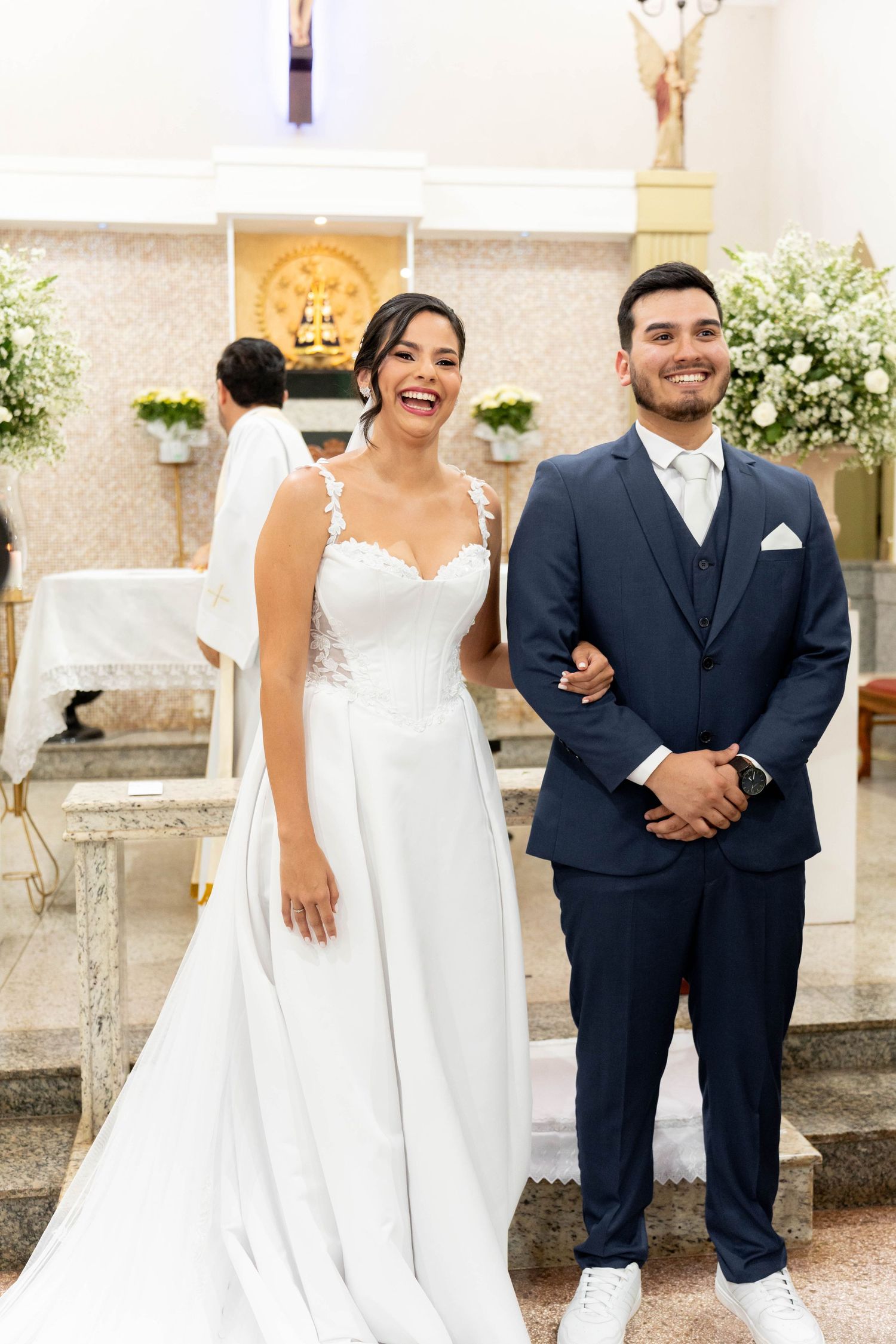 Happy bride and groom smiling together at church altar during wedding ceremony.