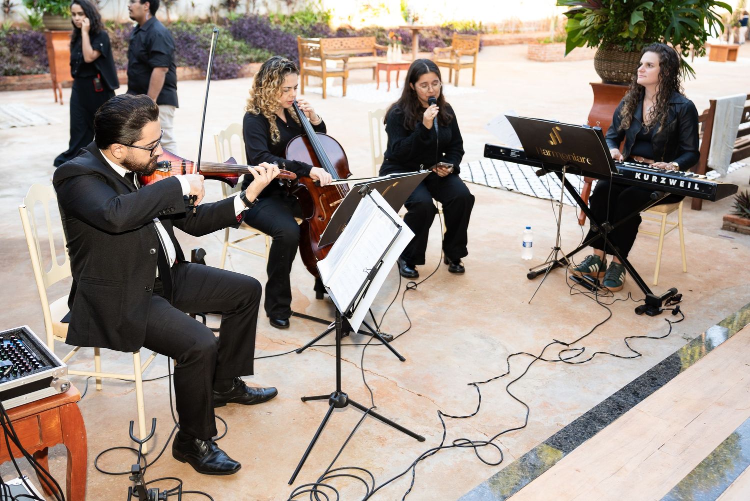 String quartet performing at an elegant indoor event, featuring violin, cello, and keyboard musicians in formal attire.