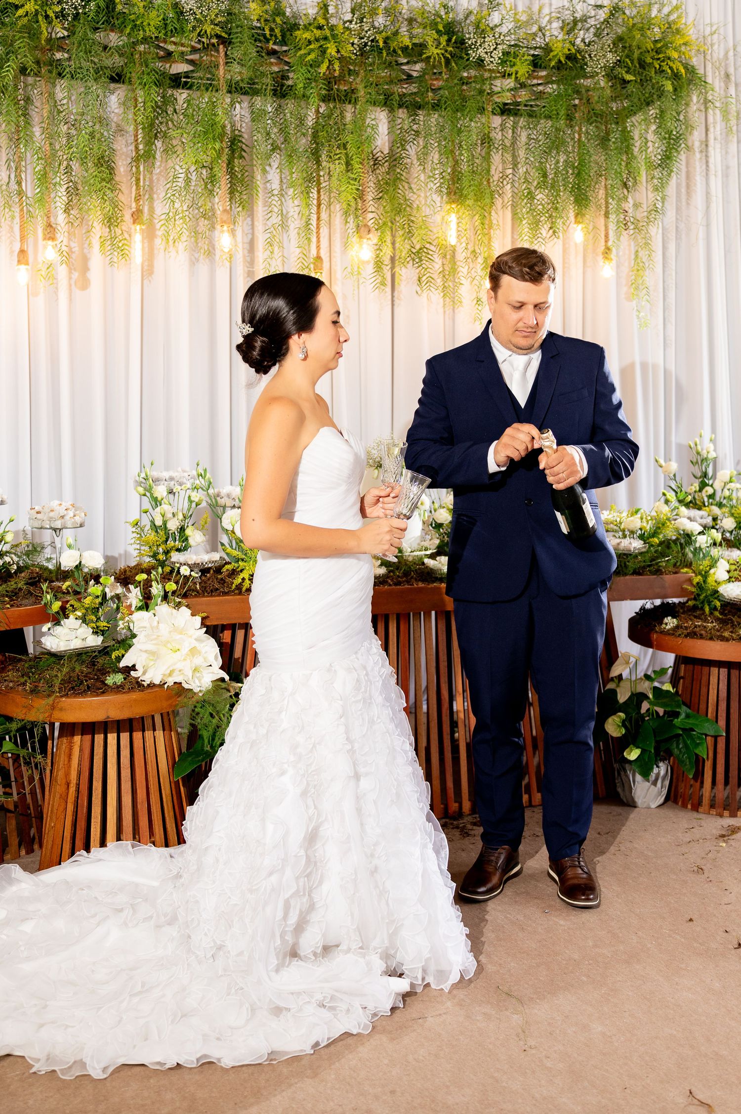 Bride and groom exchanging rings at elegant wedding ceremony with lush greenery and floral decorations.