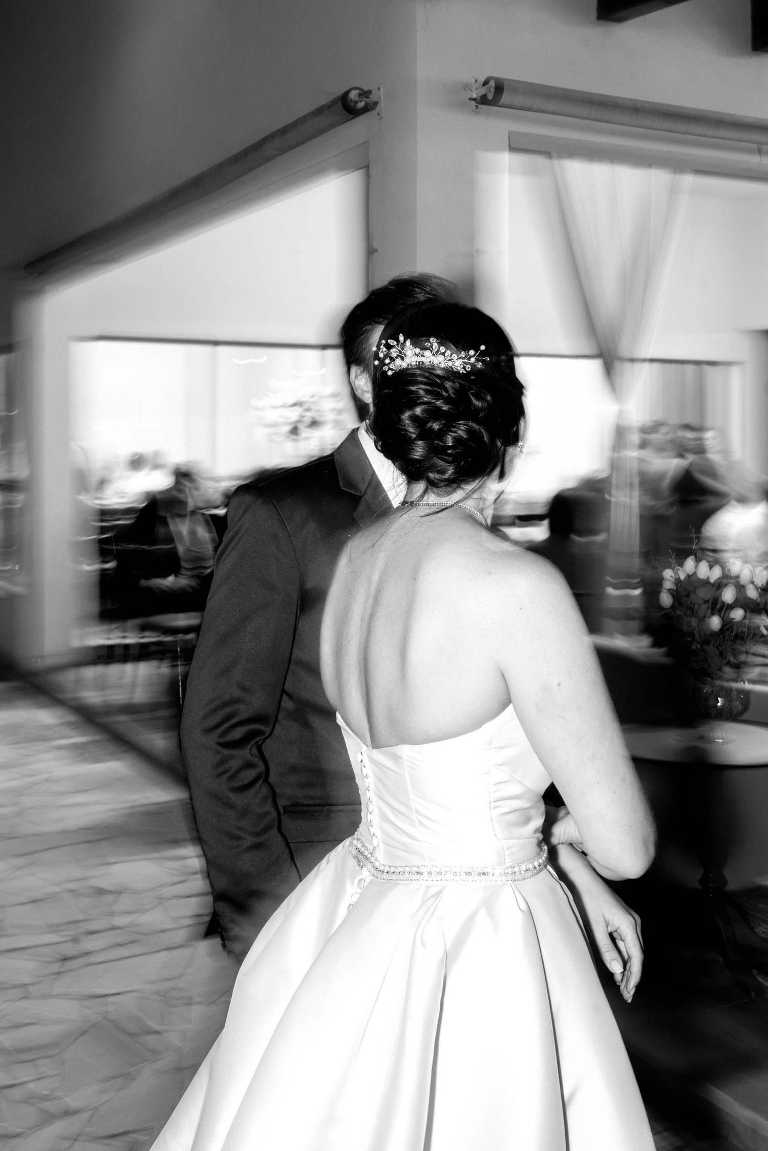 Bride and groom sharing first dance in black and white wedding photo.