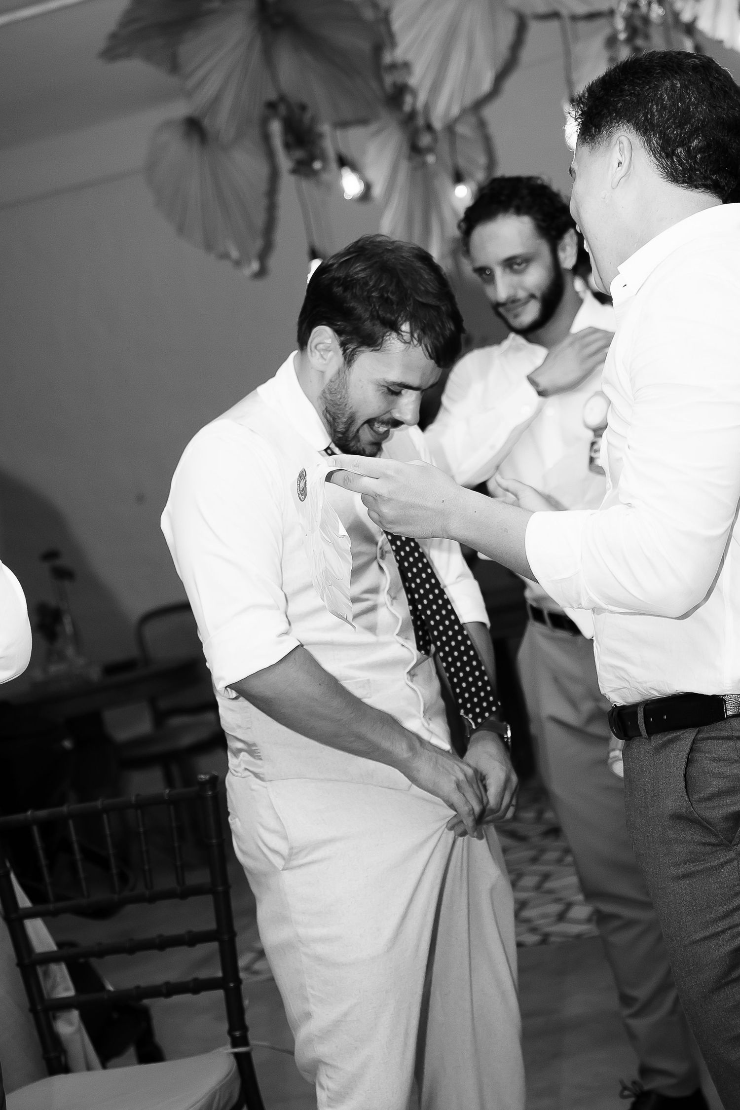 Black and white photo of men in dress shirts and ties at a formal event or wedding reception.