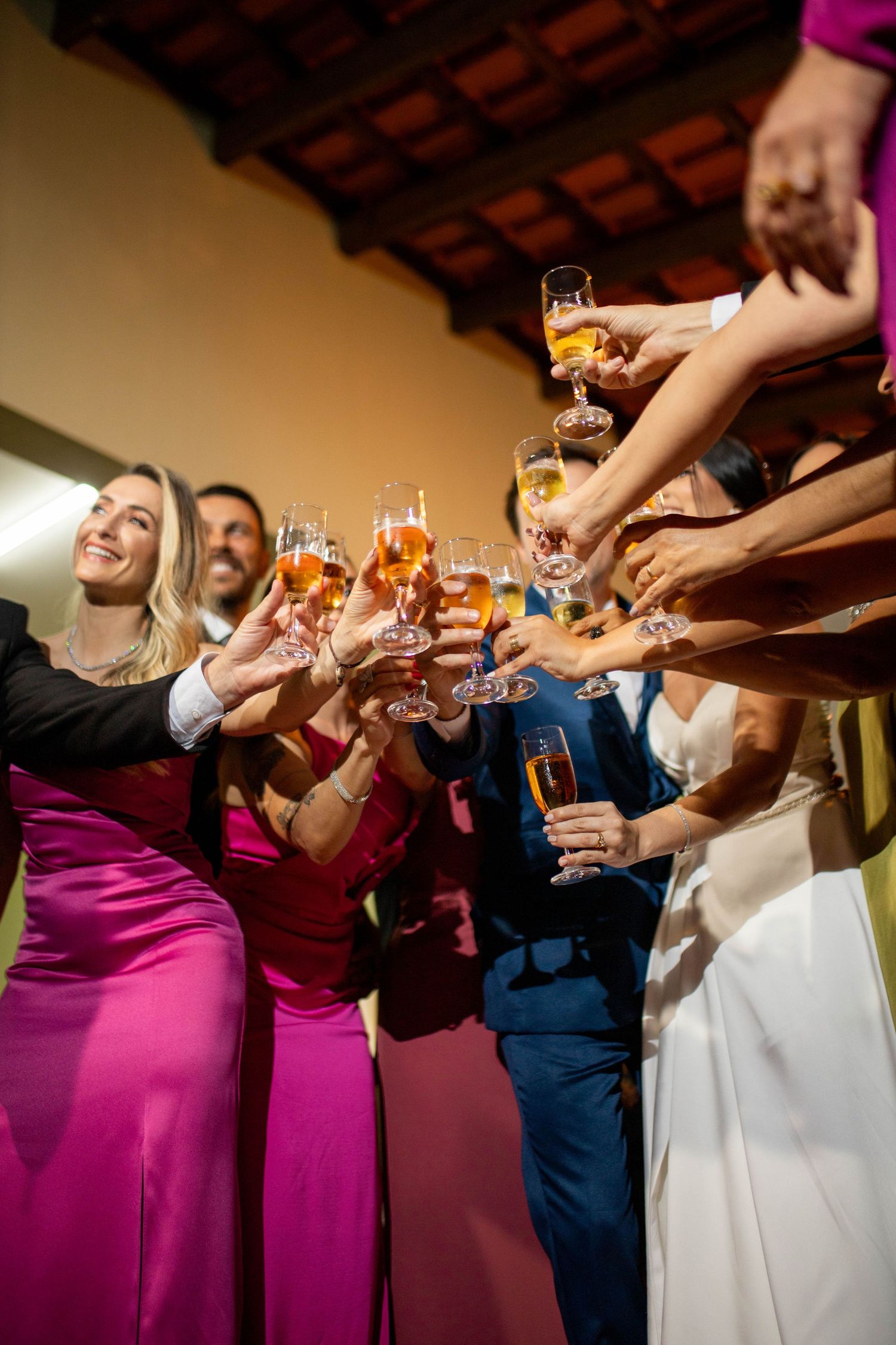 Wedding guests in formal attire raising champagne glasses in a celebratory toast at an elegant reception.