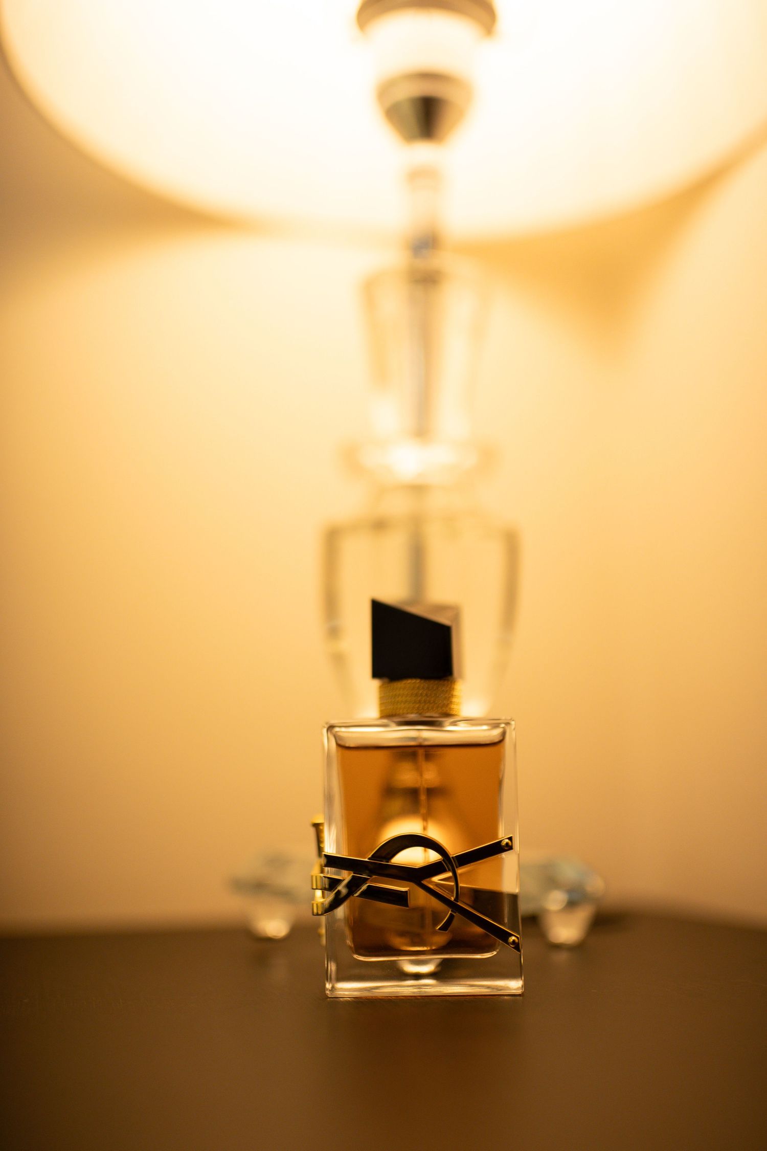 YSL Libre perfume bottle in golden light with elegant glass design on dark surface.