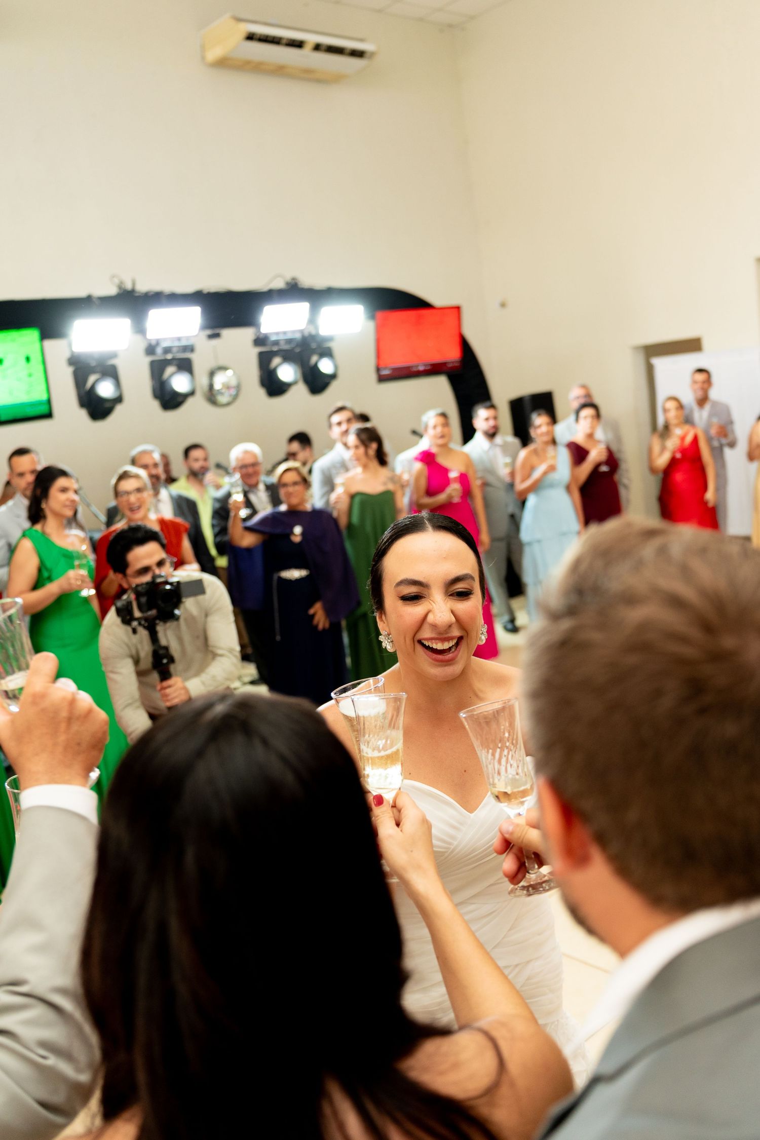 Bride in white dress toasting champagne with guests at a wedding reception celebration.
