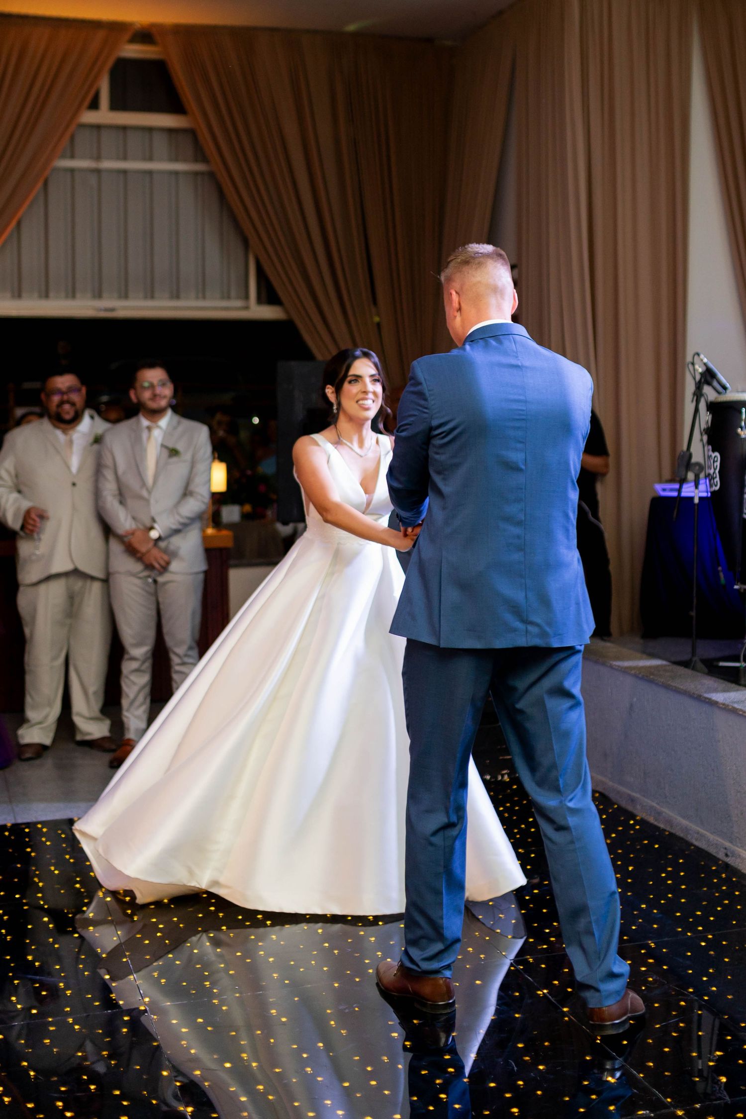 Bride and groom share their first dance on a starlit floor at an elegant wedding reception.