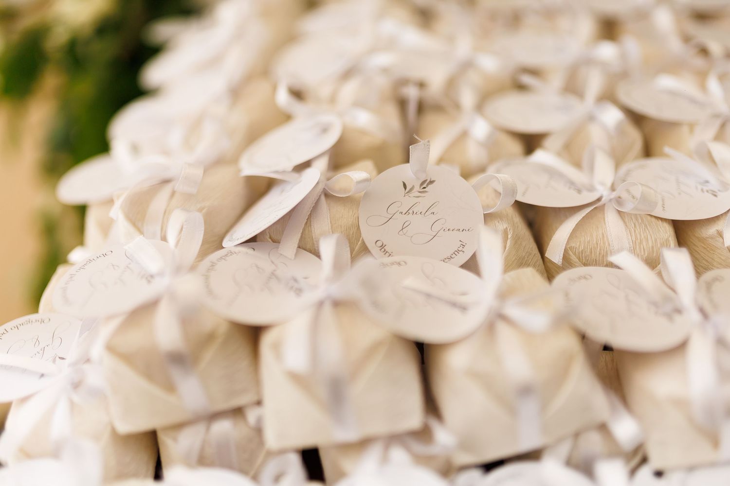 Elegant white wedding favor boxes with ribbon bows and circular tags arranged in a decorative display.