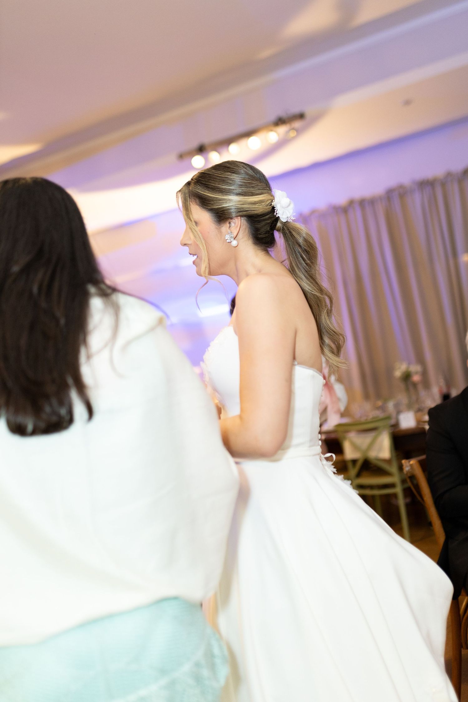 Bride in white strapless gown laughing with guest at elegant wedding reception venue.