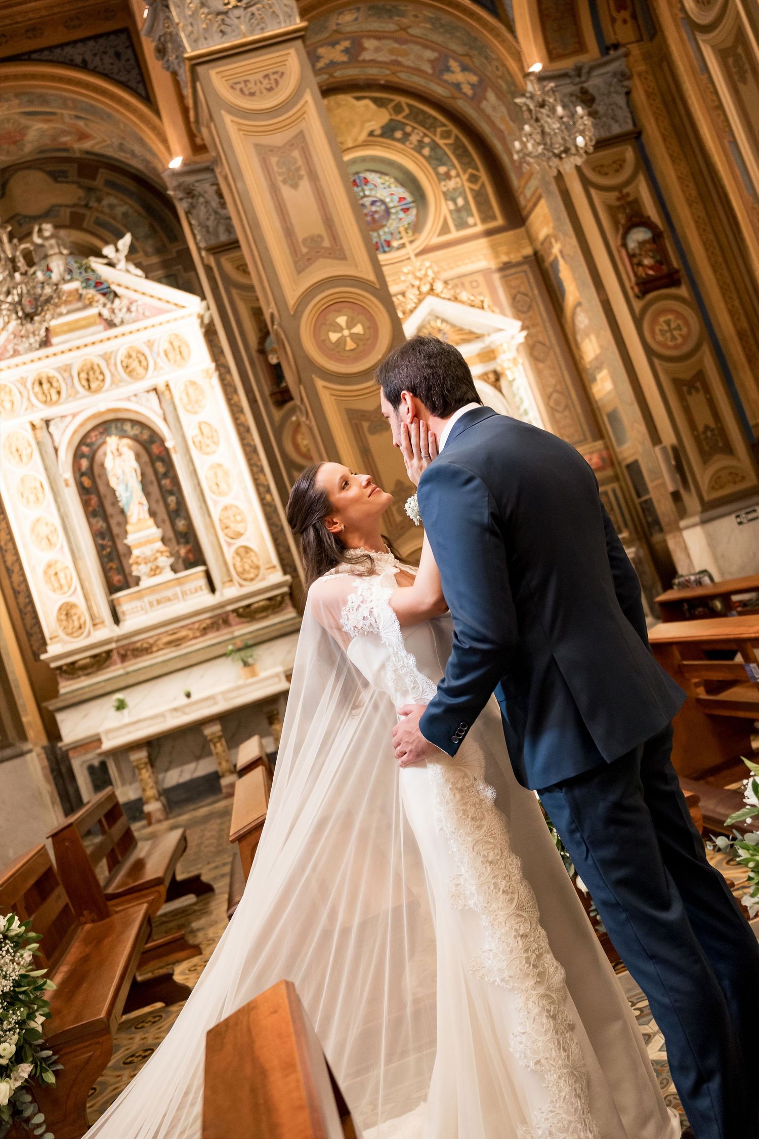 Bride and groom share a romantic kiss at the altar of an ornate golden church during their wedding ceremony.