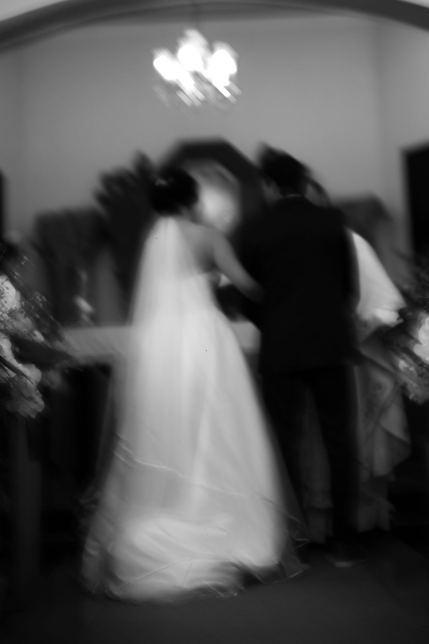 Blurred black and white photo of bride and groom sharing first dance at wedding.